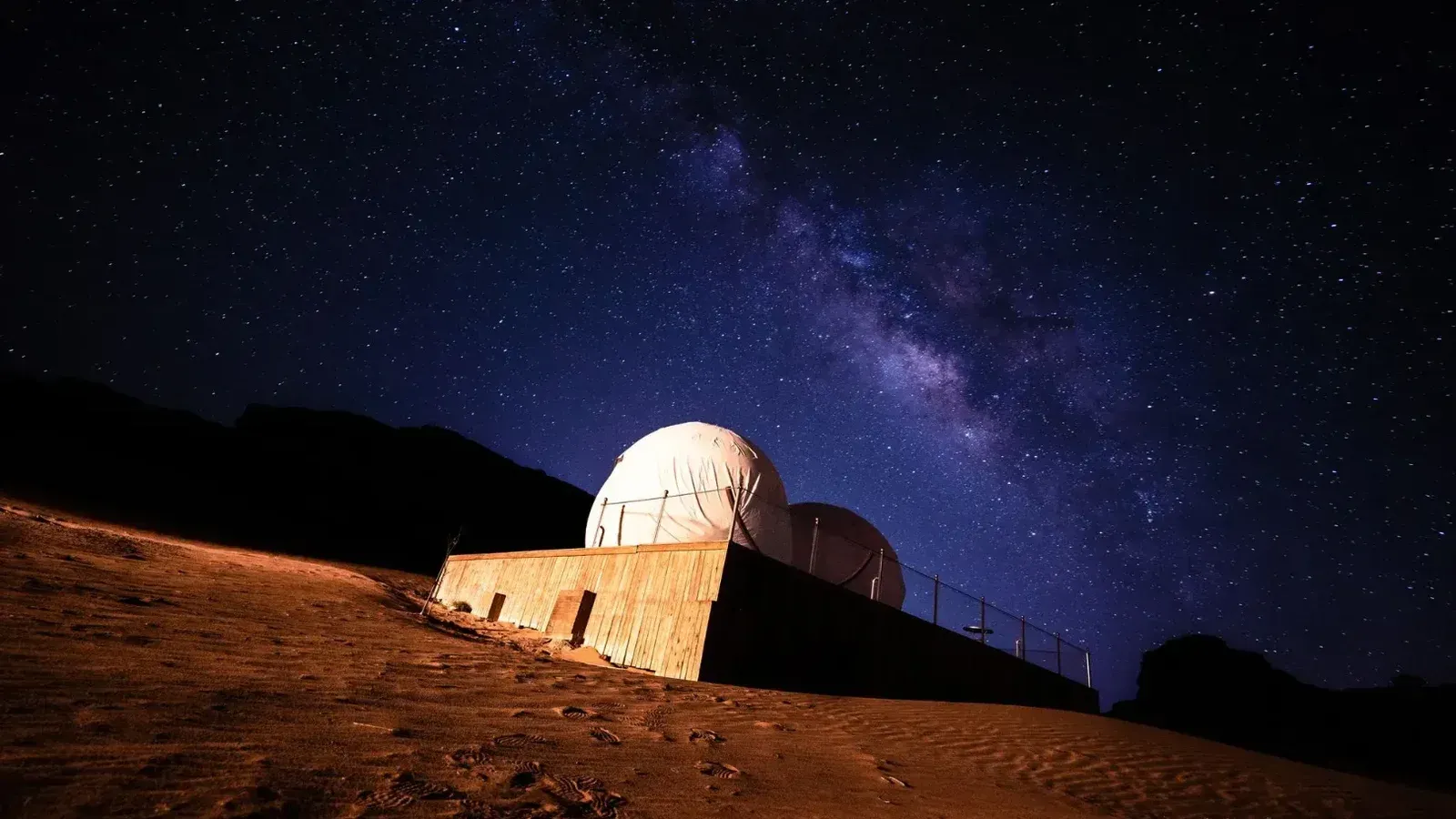 Impresionante vista de la galaxia de la Vía Láctea sobre un observatorio del desierto bajo una noche estrellada.