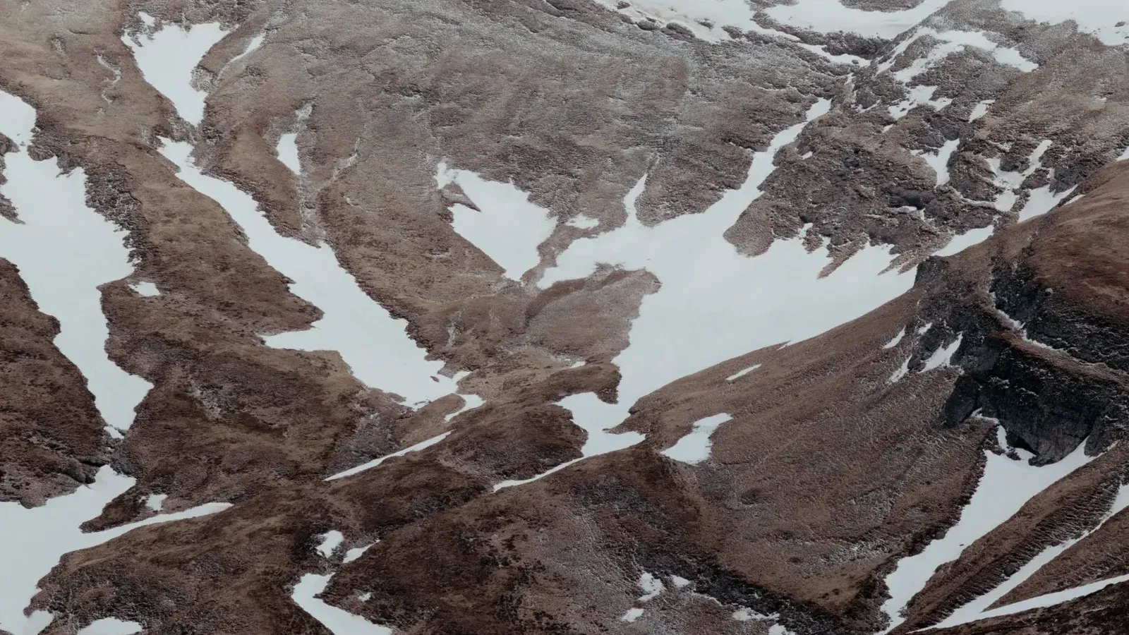 Aerial view of the snow-capped mountains in Bușteni, Romania, showcasing rugged terrain.