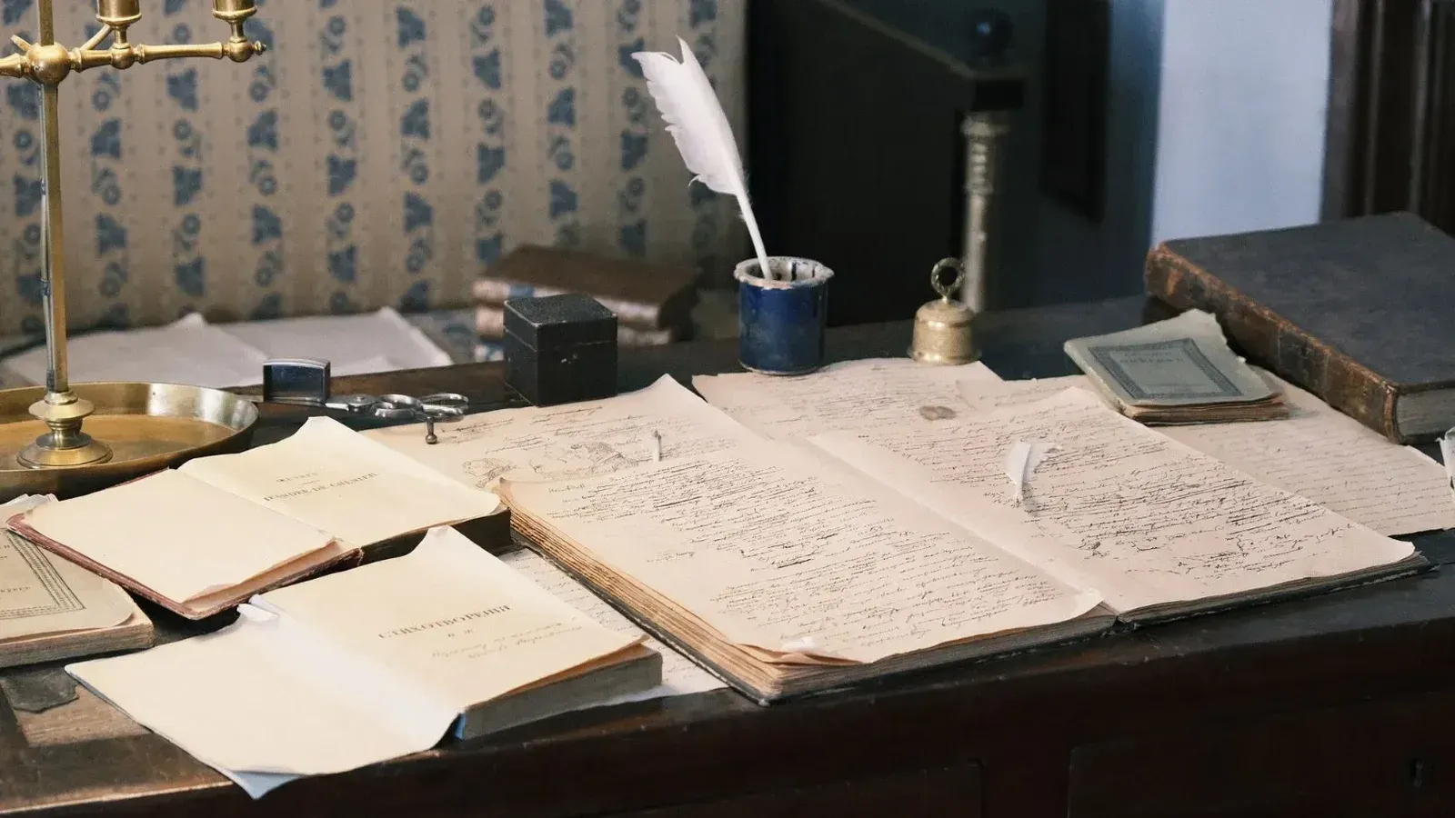 Acogedor estudio con escritorio vintage, libros abiertos y pluma para una sensación literaria clásica.