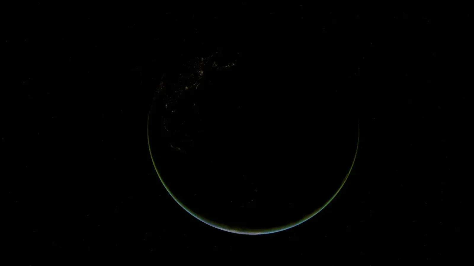 Stunning crescent view of Earth at night, highlighting city lights and vast oceans.