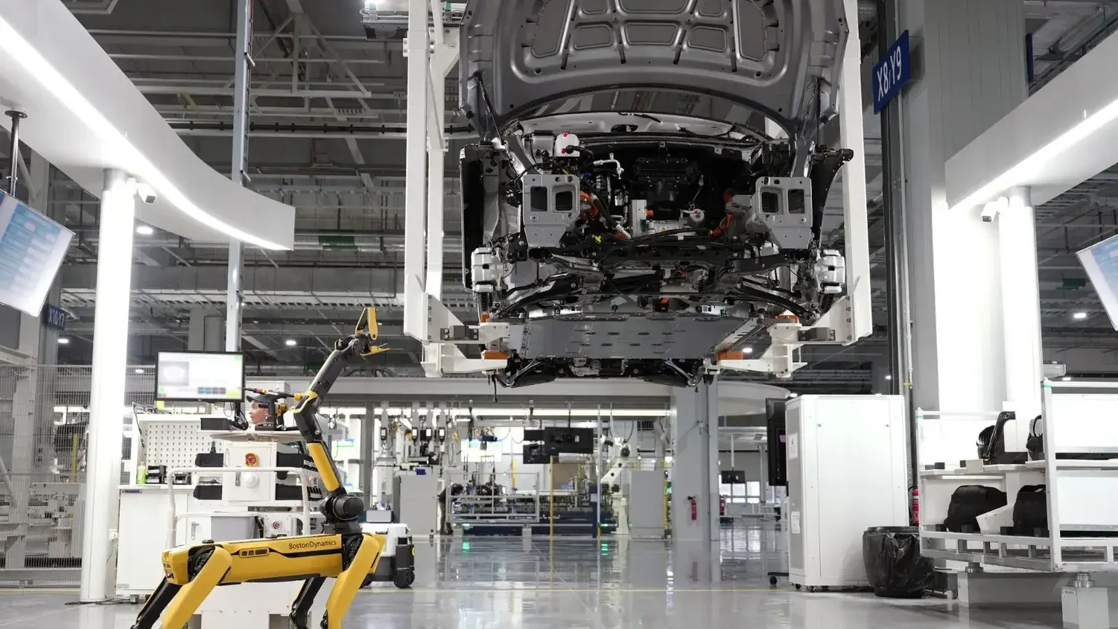 Un perro robótico supervisa un ensamblaje de automóviles automatizado en un entorno de alta tecnología de fábrica.