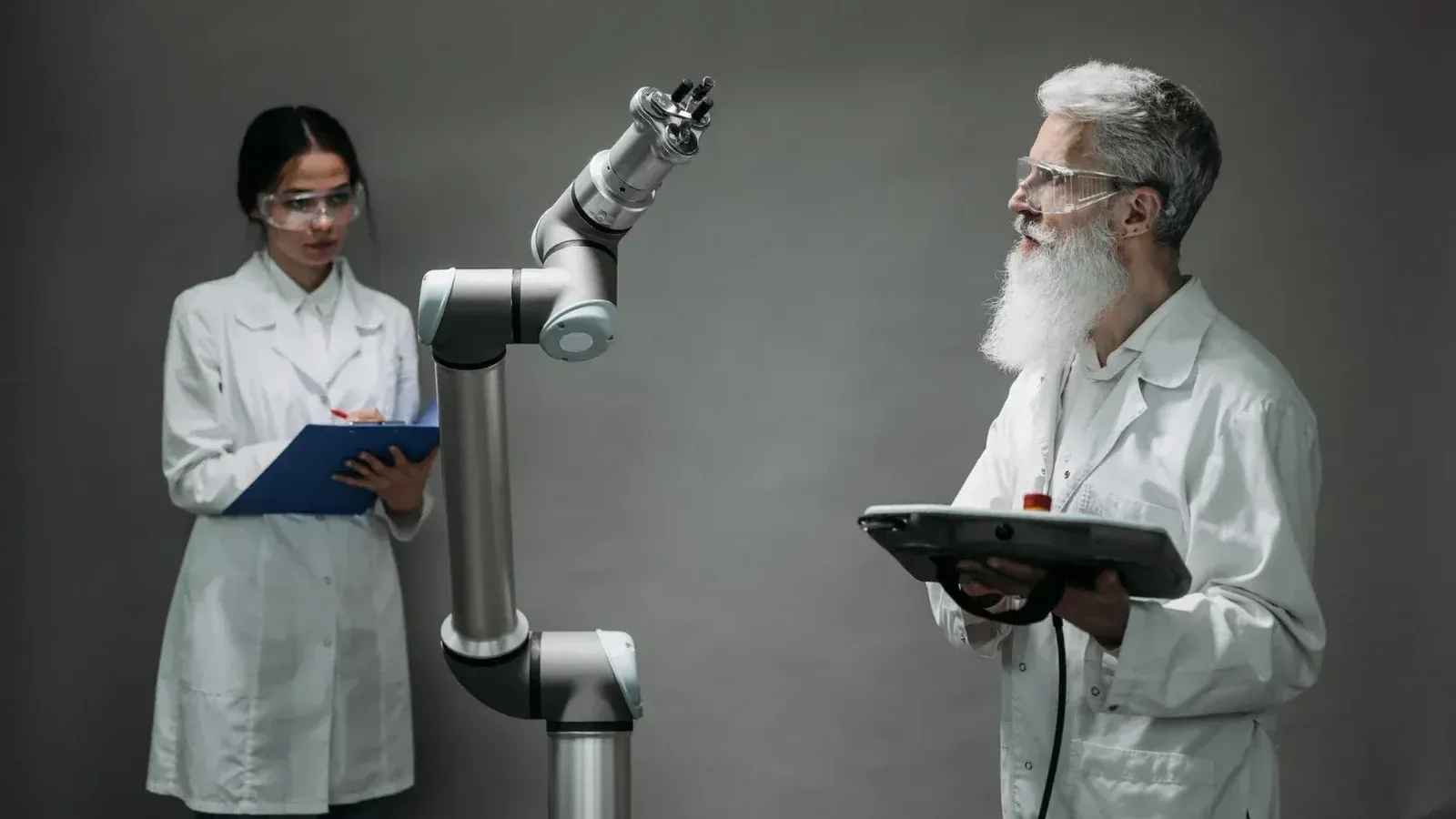 Two scientists working with a robotic arm in a lab setting, focusing on innovation and technology.