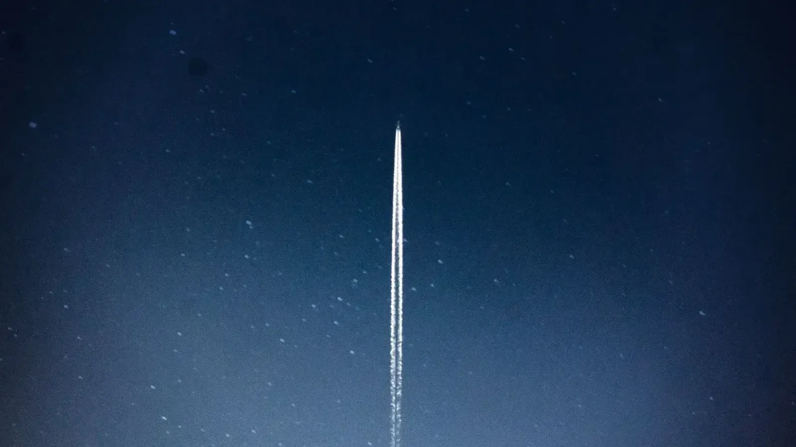 A rocket streaks through a starry night, leaving a trail in outer space.