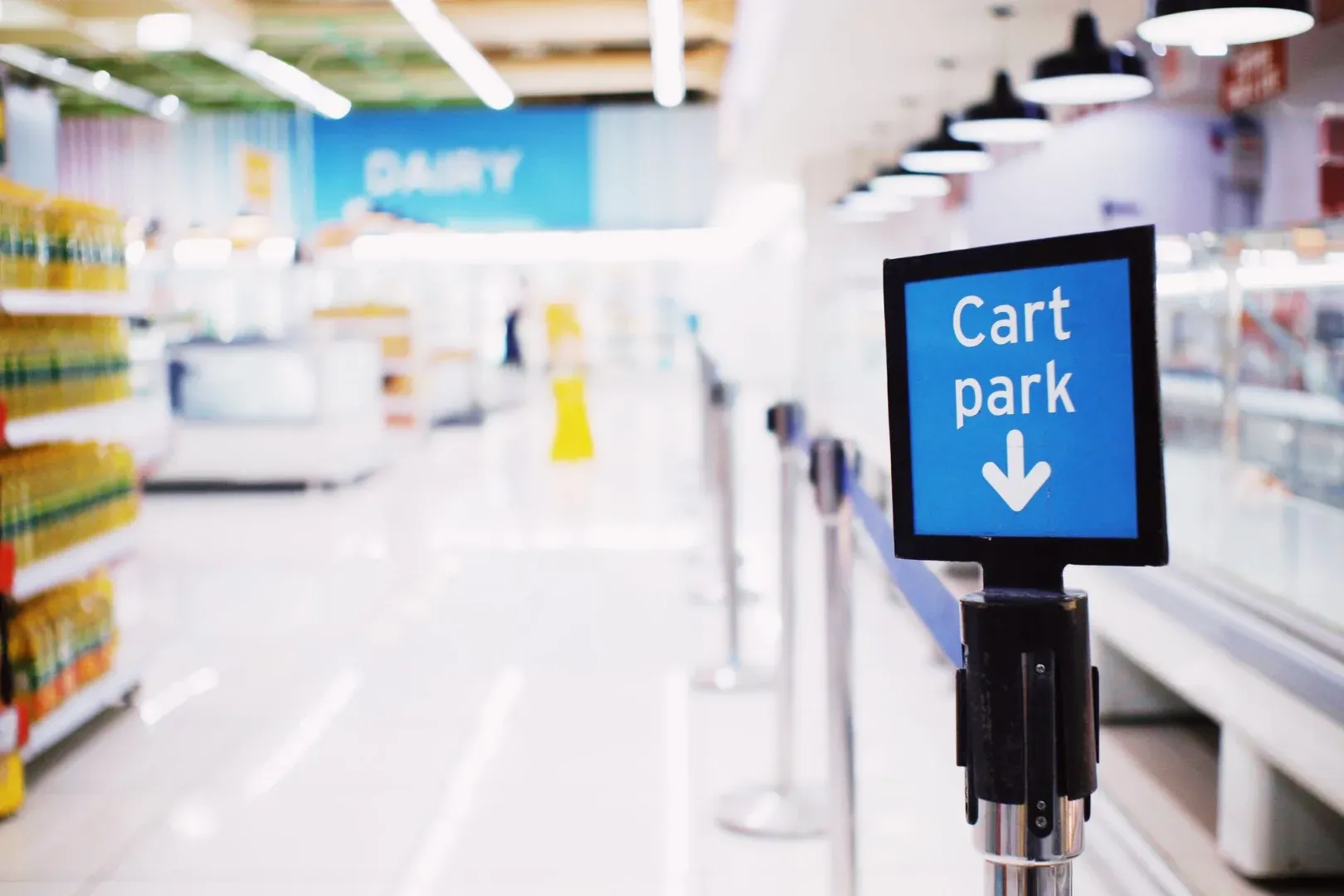 Letrero azul con parque de carritos de inscripción colocado cerca del mostrador con productos en el supermercado contemporáneo