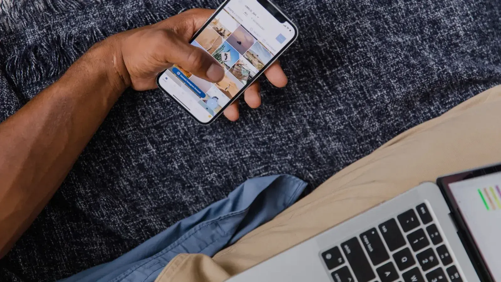 Mano que sostiene el smartphone con la computadora portátil abierta, que muestra el estilo de vida digital moderno.