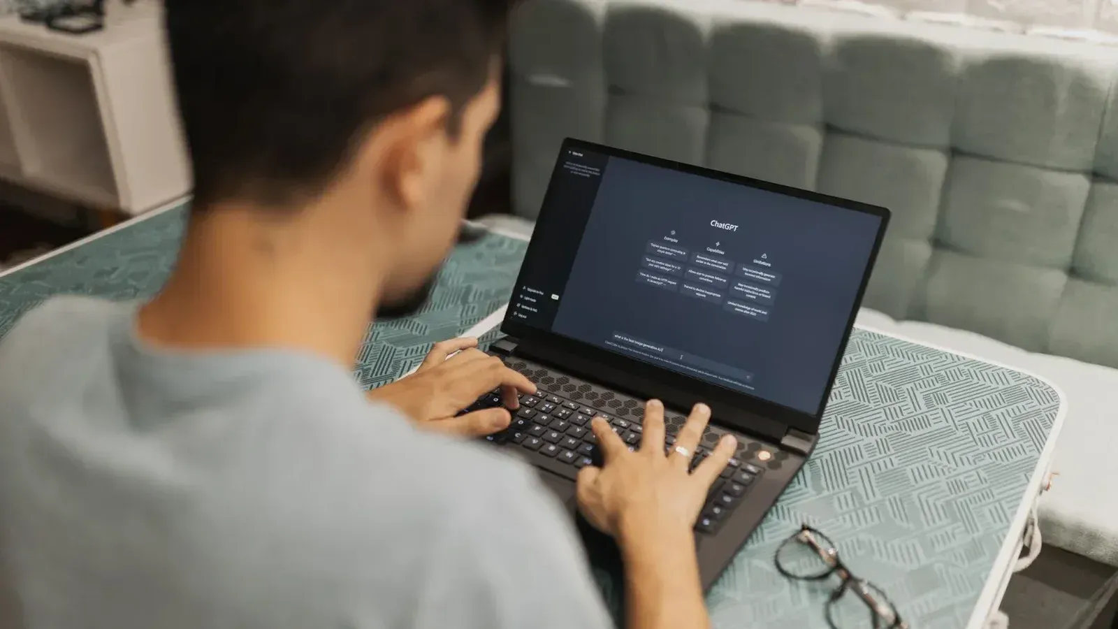 A man working on a laptop displaying ChatGPT's interface in an indoor setting.
