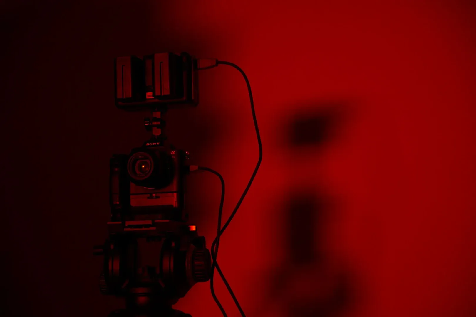 Minimalist close-up of a camera setup in dramatic red lighting, perfect for creative photography projects.