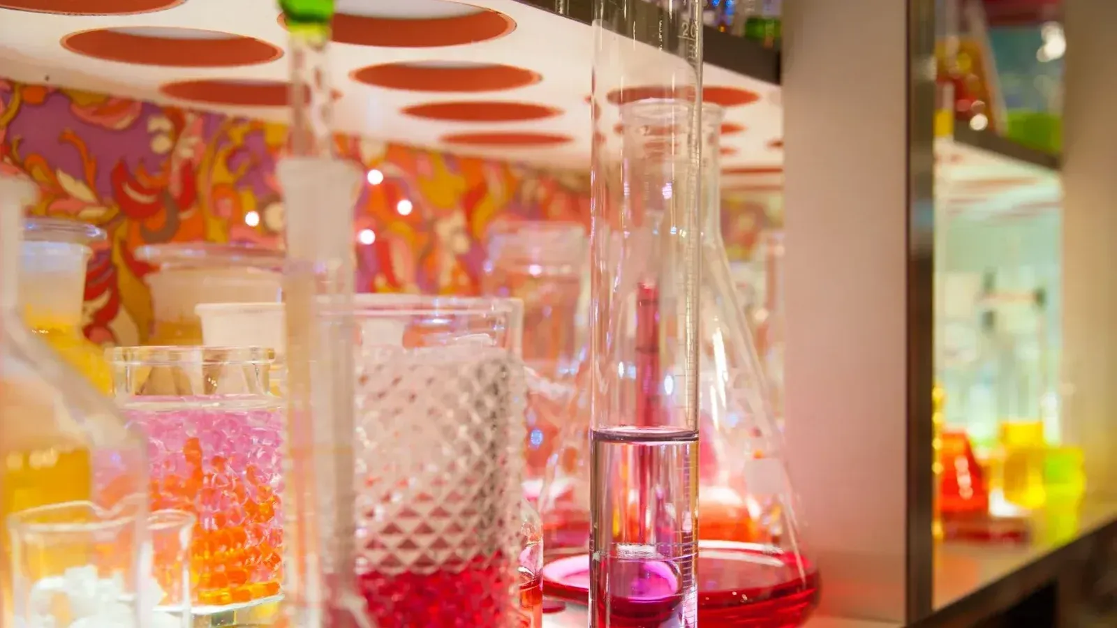 A collection of colorful glassware with vibrant liquids on display in a lab setting.