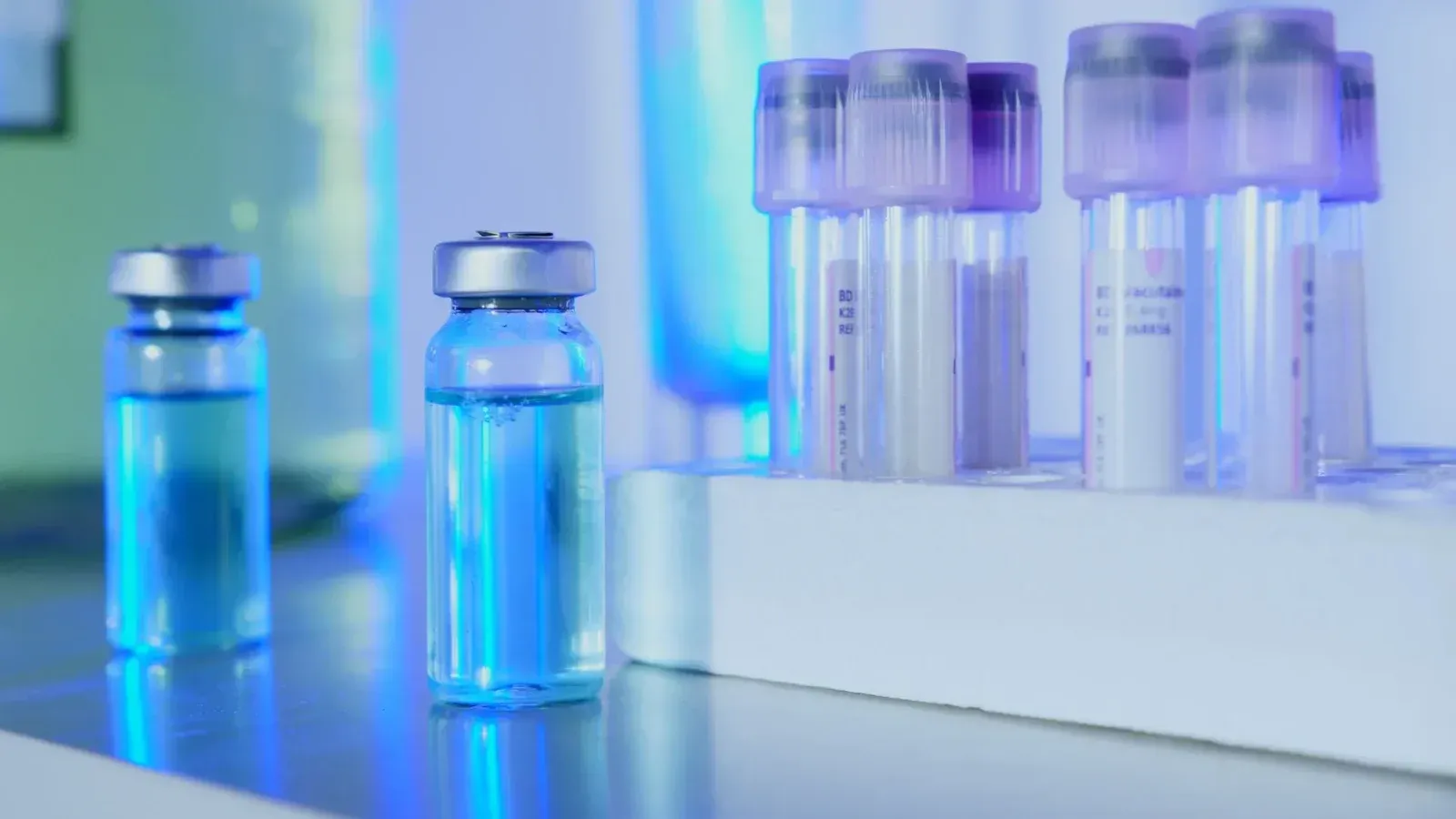 Viales y tubos de ensayo con líquido azul en un laboratorio bajo luz fluorescente.