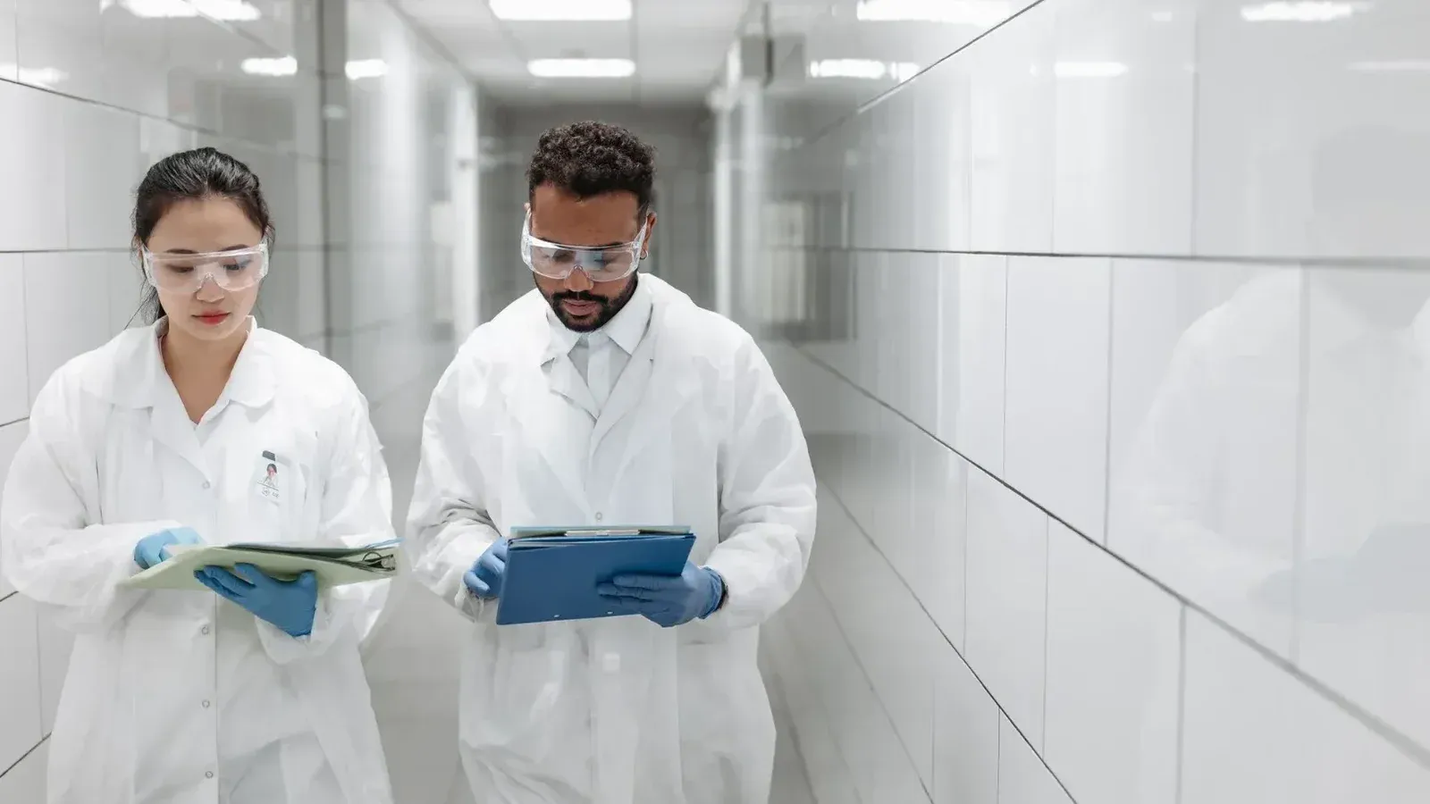 Dos investigadores en batas de laboratorio revisan los documentos en un pasillo de laboratorio clínico.