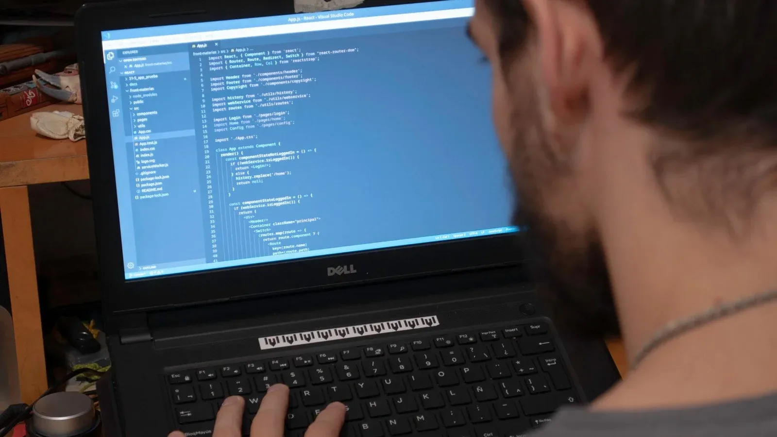 Man working on code on a laptop in an office, showcasing modern remote work setup.