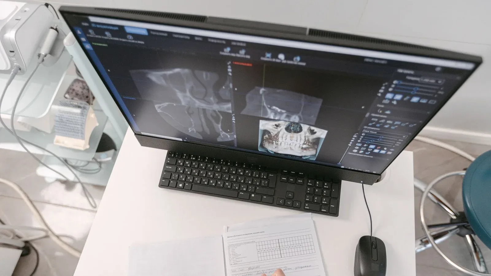 Radiologist analyzing X-ray scans on a computer monitor while taking notes. Medical documents visible.