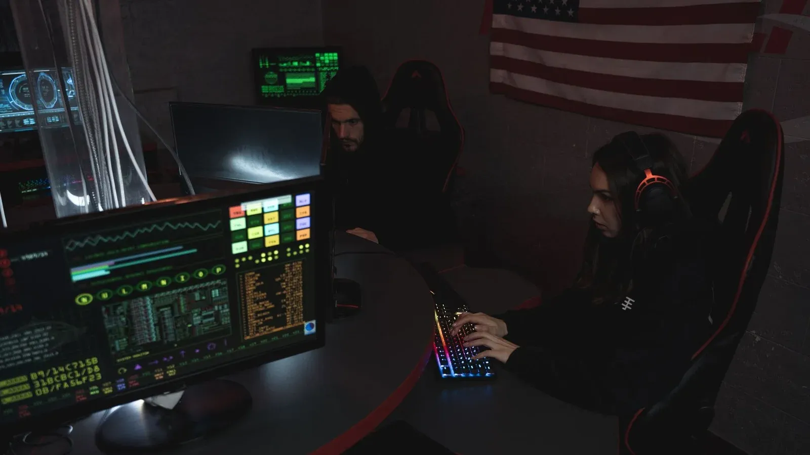 Cybersecurity professionals working on computer systems, focusing on data protection in a dimly lit room.