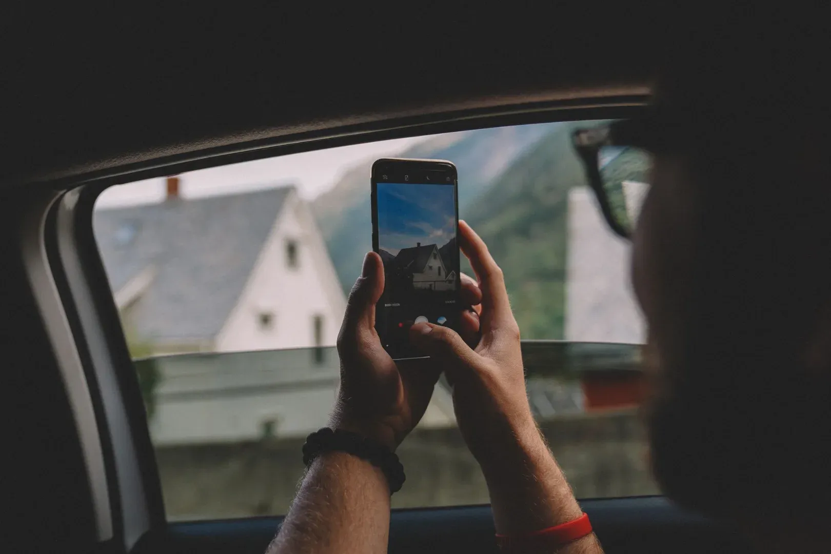 Person takes photo of scenic view from car window with smartphone in Norway.