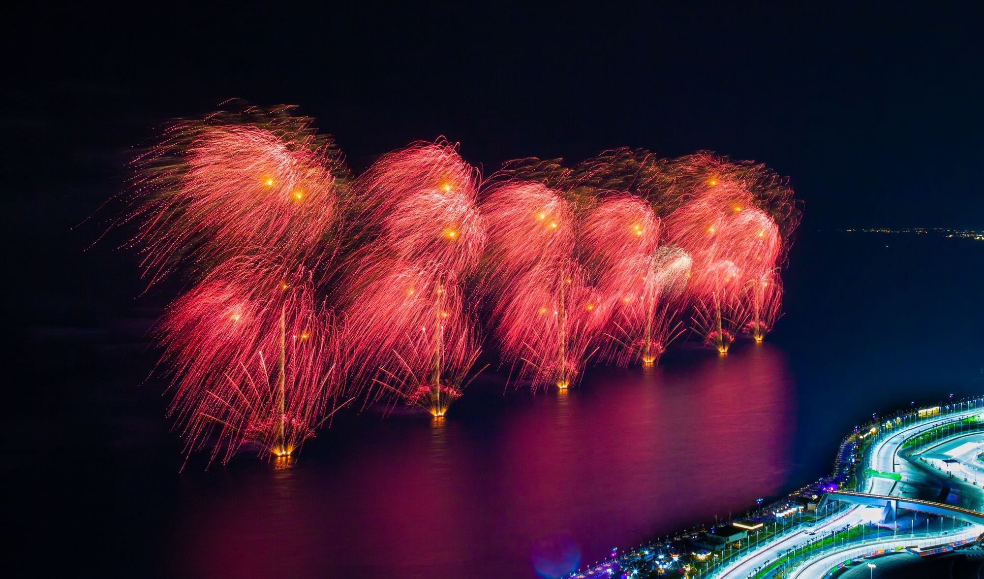 Vibrant fireworks display over the sea captured from above, showcasing the night sky's brilliance.