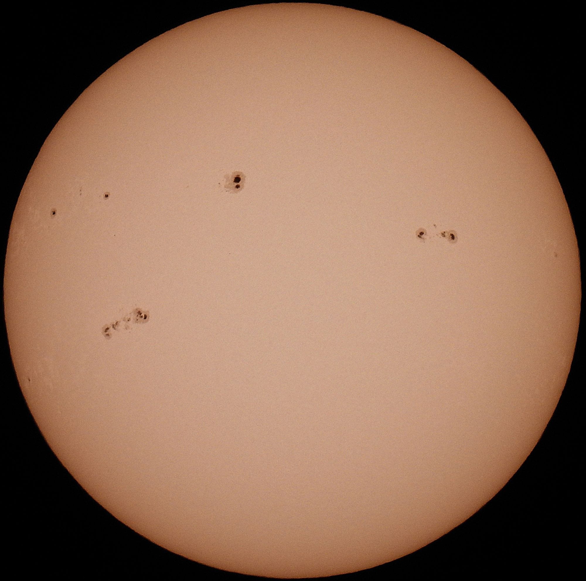 Close-up of the sun with visible sunspots, showcasing solar surface details.