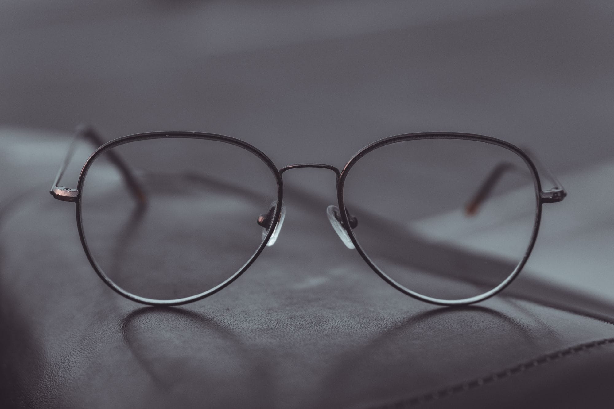 Stylish aviator glasses resting on a leather surface, showcasing sleek design.