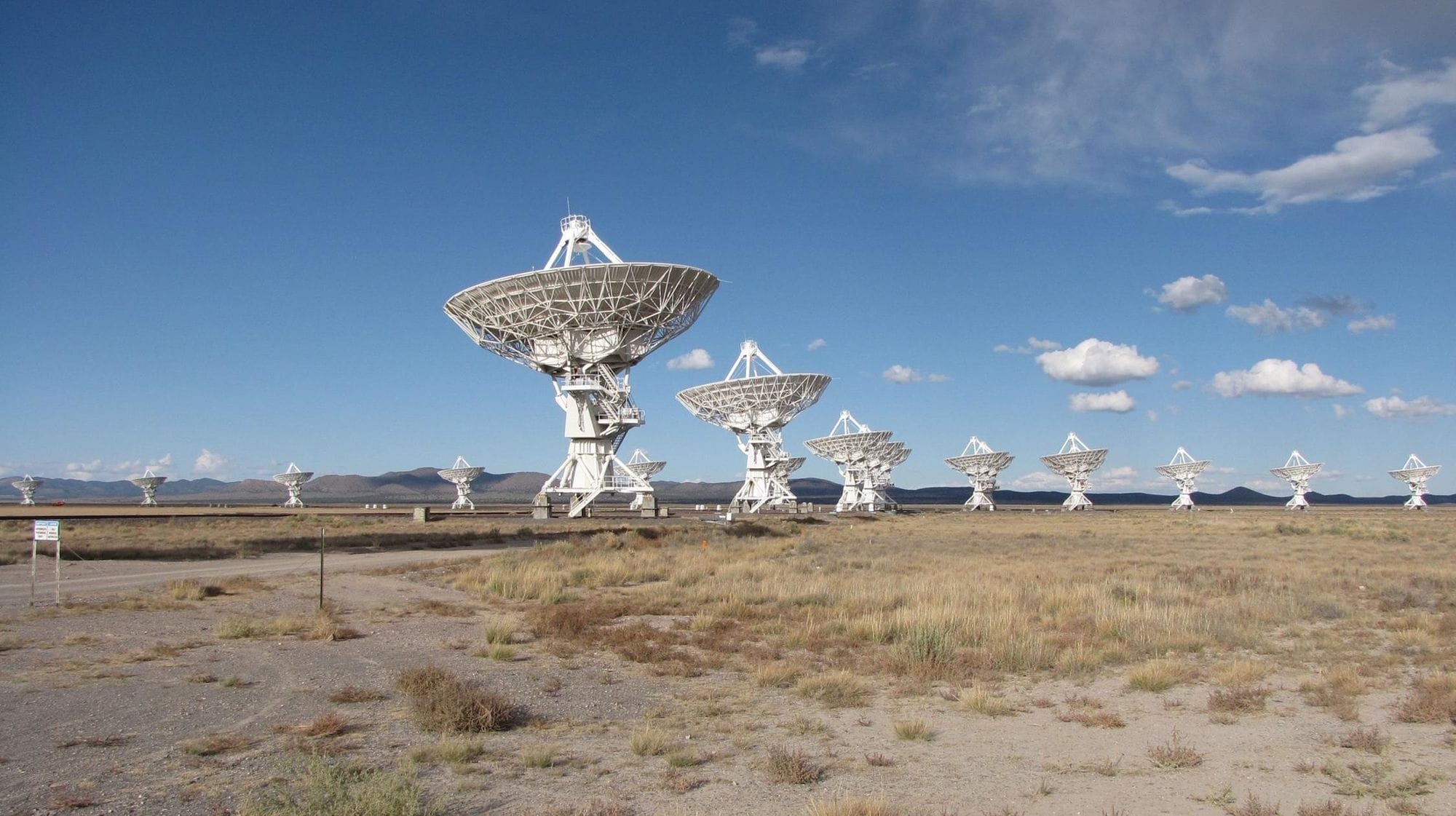 Explore the expansive array of radio telescopes in open terrain under a vibrant blue sky.