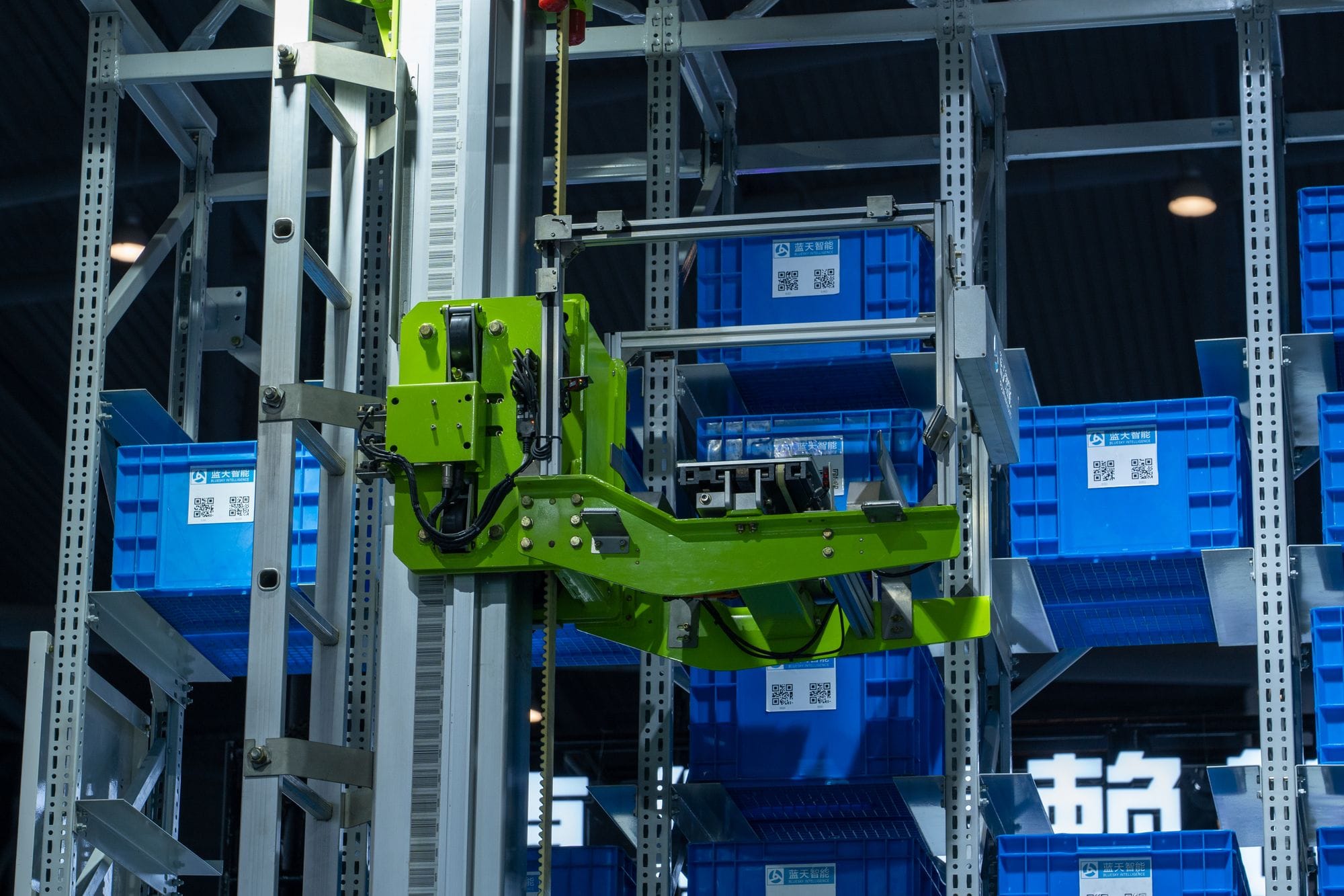 High-tech automated warehouse system featuring a green robotic arm handling blue storage crates.