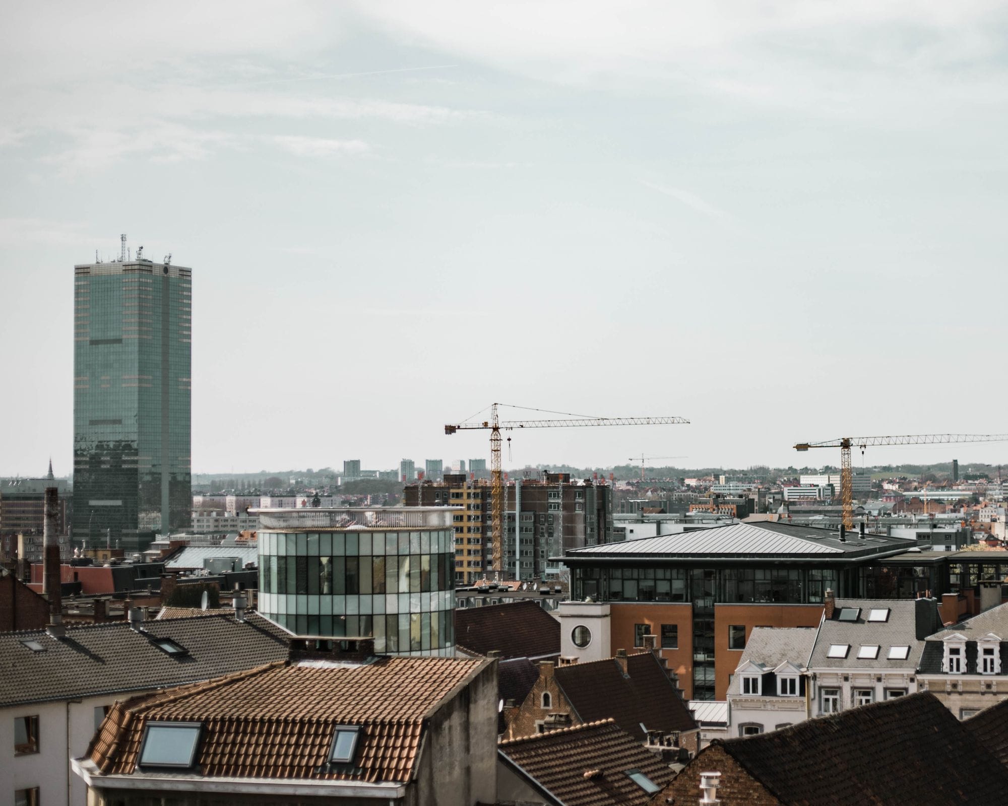 Urban skyline of Brussels with cranes, showcasing modern architecture and city development.