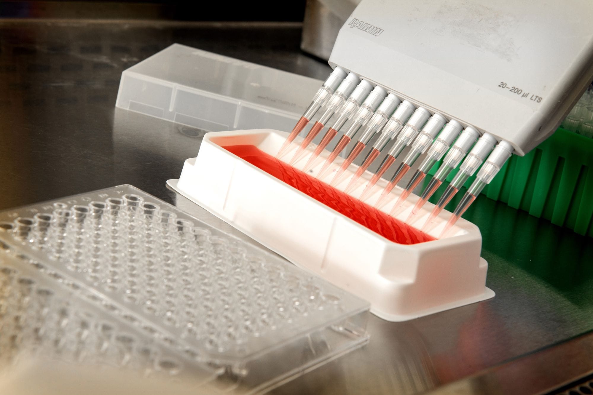 Close-up of an automated pipetting system dispensing liquids in a scientific laboratory.