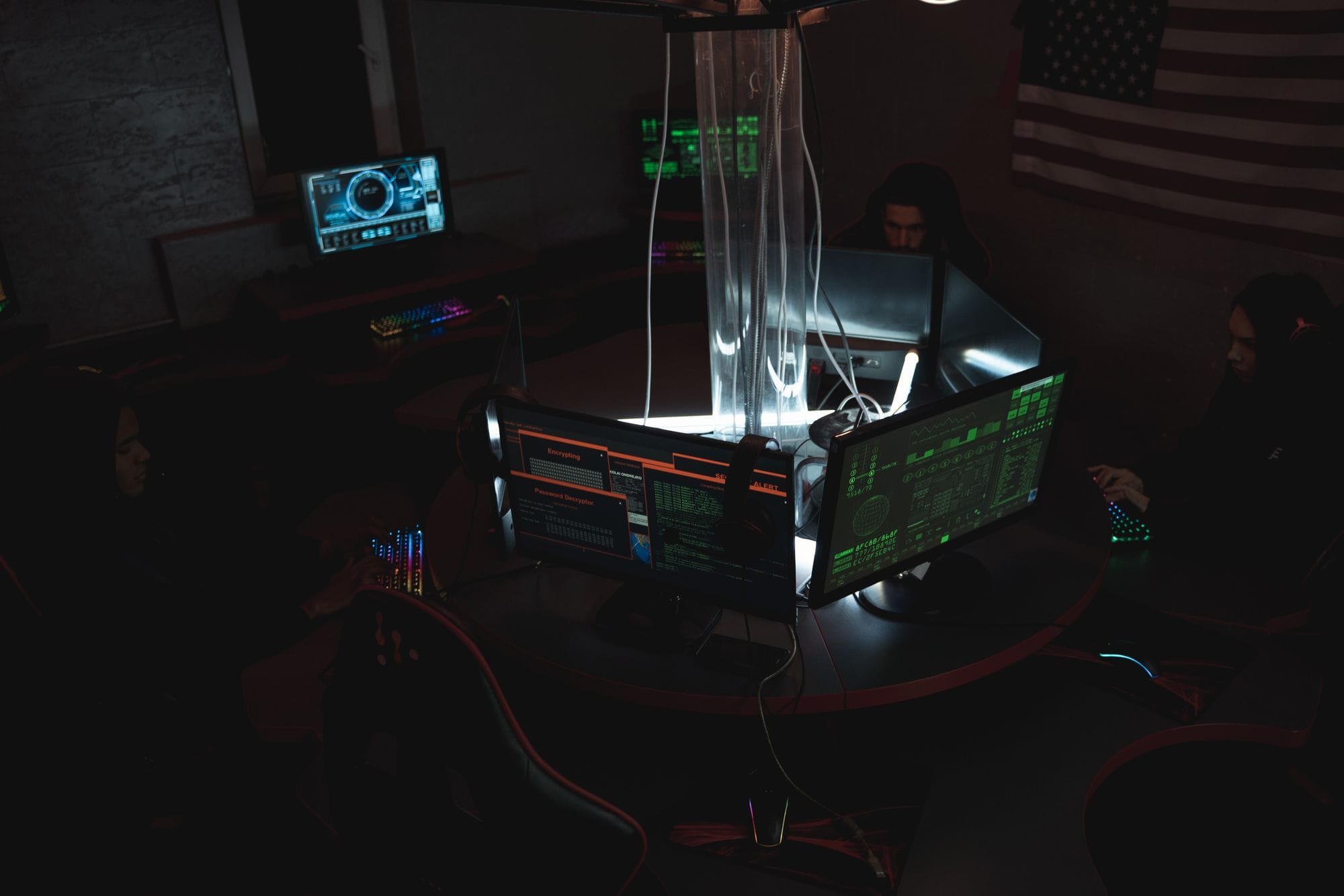 Team of cybersecurity experts collaboratively working on data protection in a dimly lit room filled with computers.