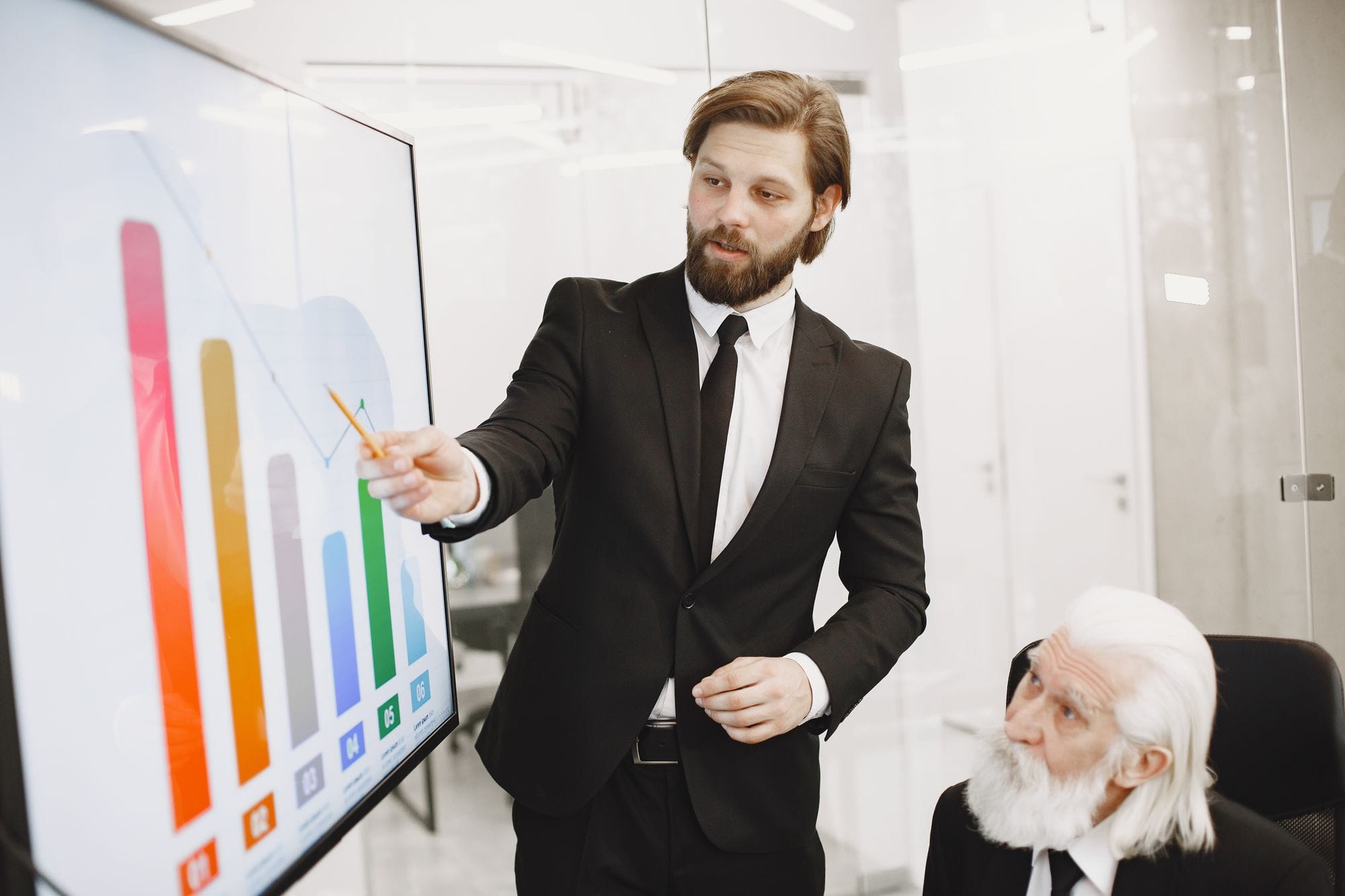 Two businessmen discussing data trends during a presentation in a modern office setting.