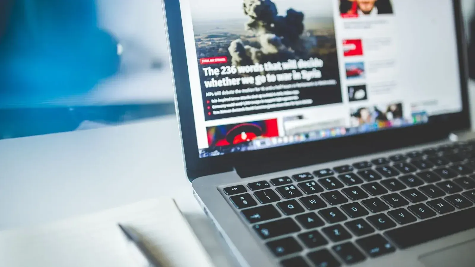 Abra la computadora portátil que muestra un artículo de noticias en línea en un escritorio con un cuaderno cerca.