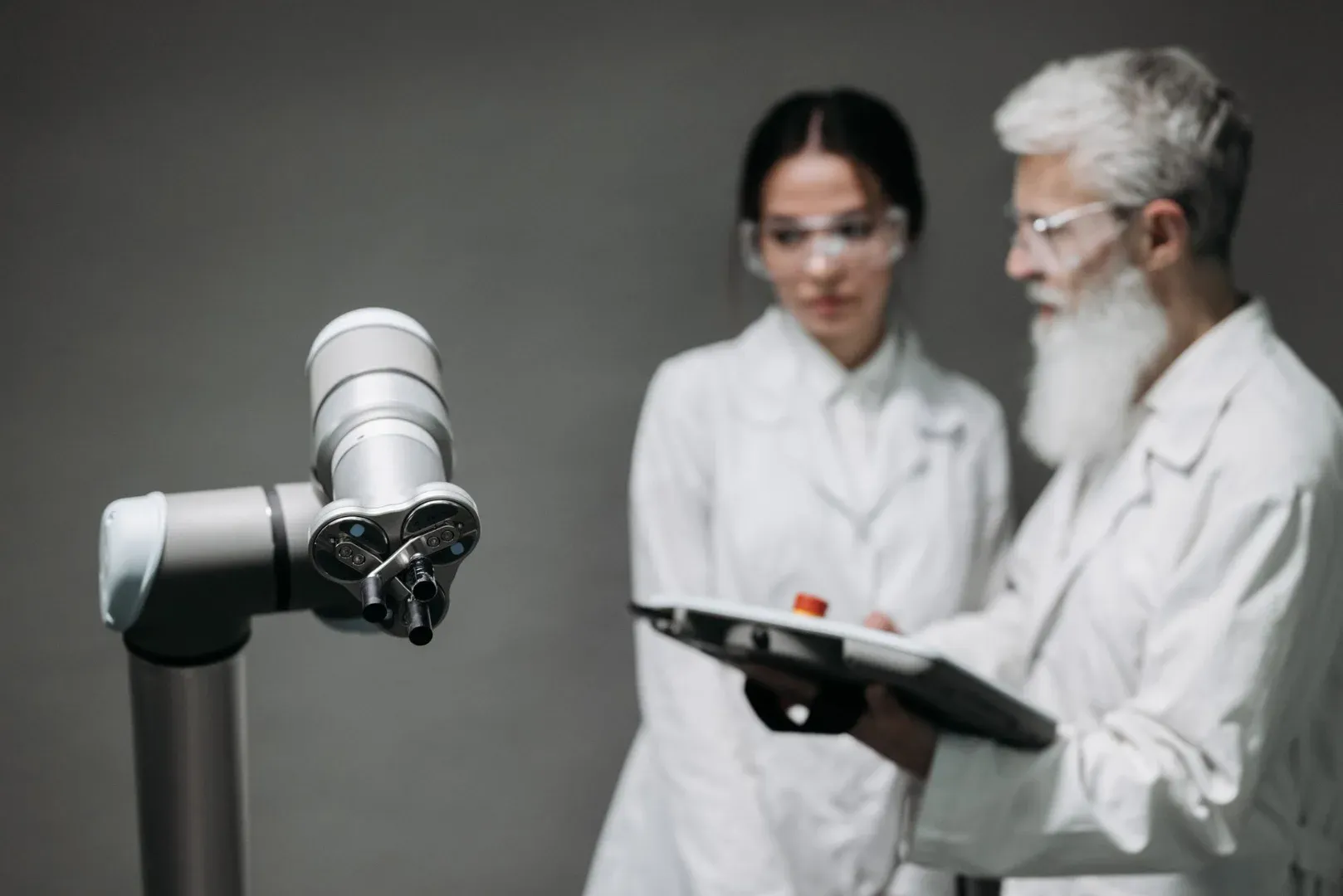 Researchers in lab coats analyze robotic equipment for technological advancement.