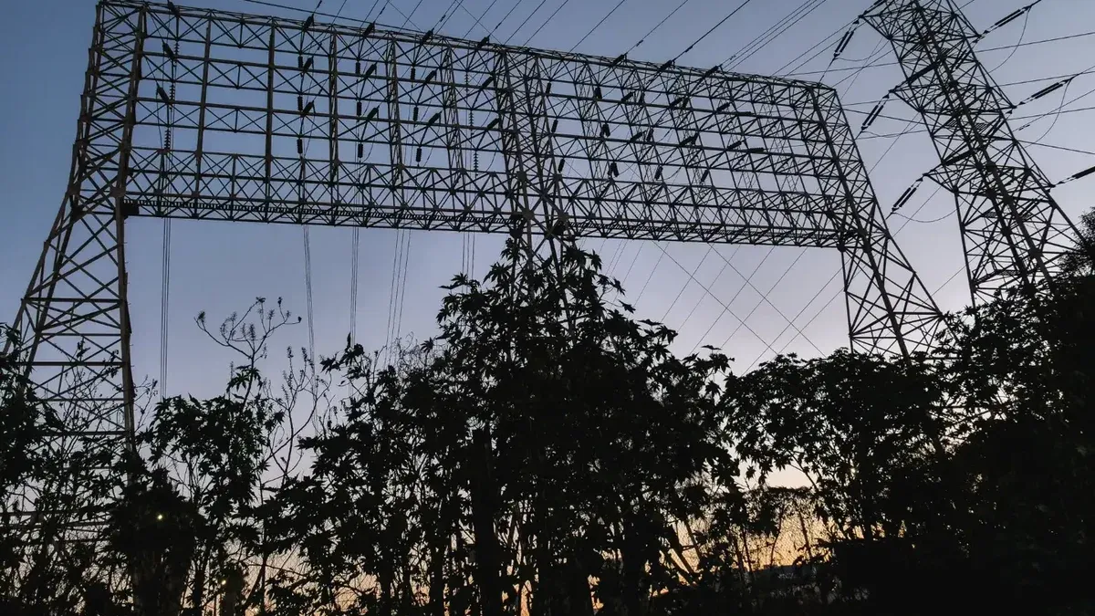 Silhouette of electricity pylons and power lines set against a twilight sky.
