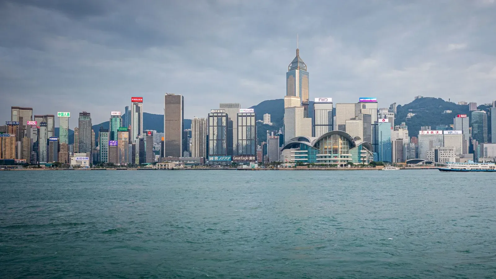 Spectacular daytime view of Hong Kong skyline with harbor in foreground.