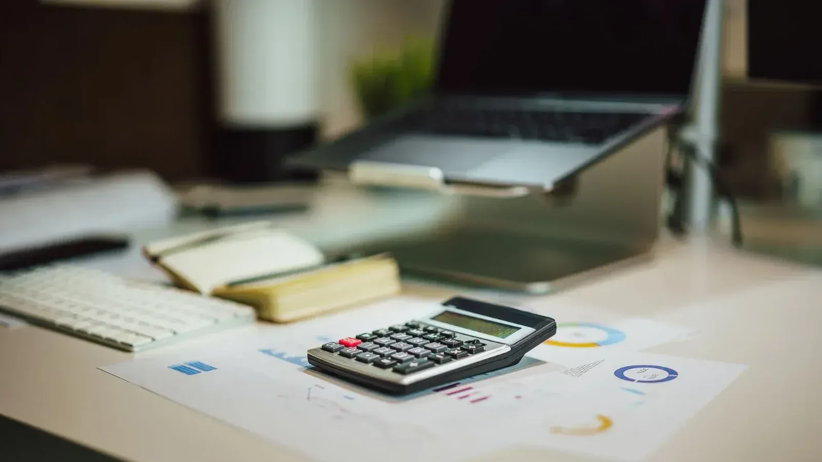 A modern workspace with a laptop, calculator, and documents on a desk, perfect for finance tasks.