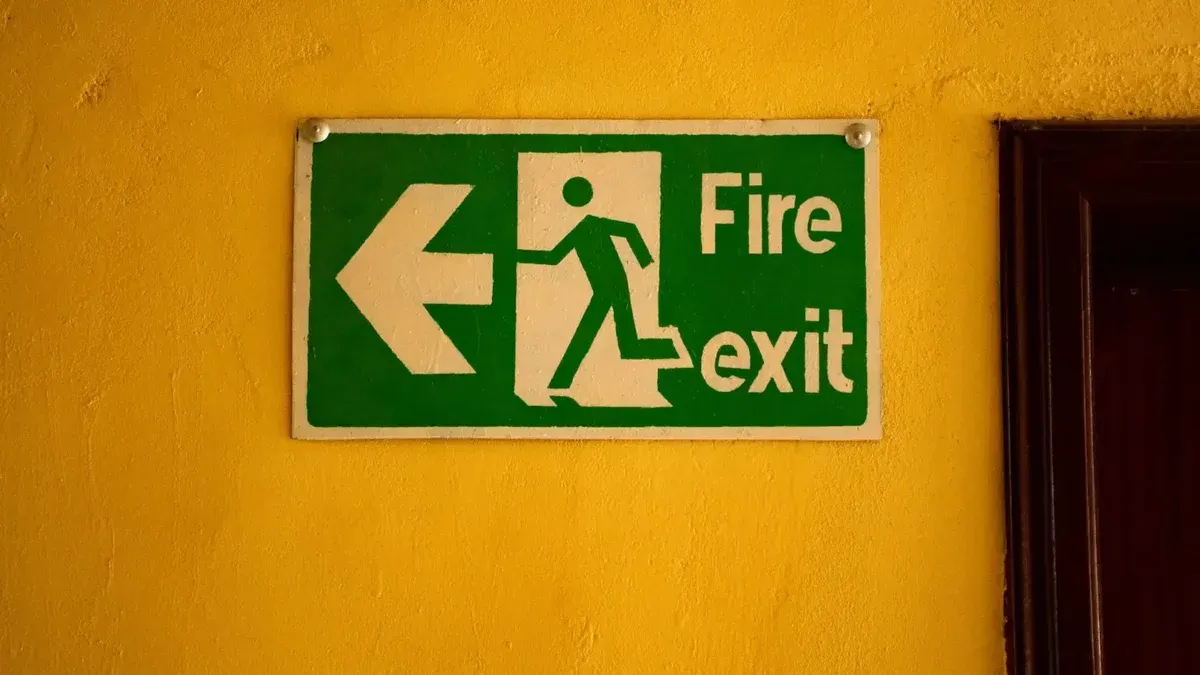 Fire exit sign on a yellow wall, indicating safety and emergency exit direction.