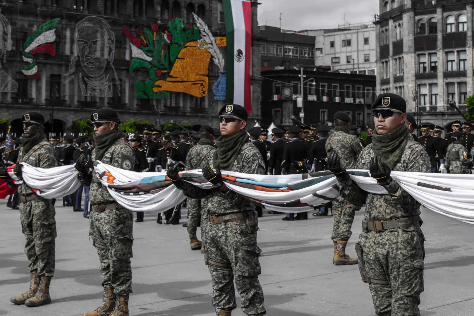 Soldiers in camouflage uniforms hold a flag during a parade in Zócalo, Mexico City.