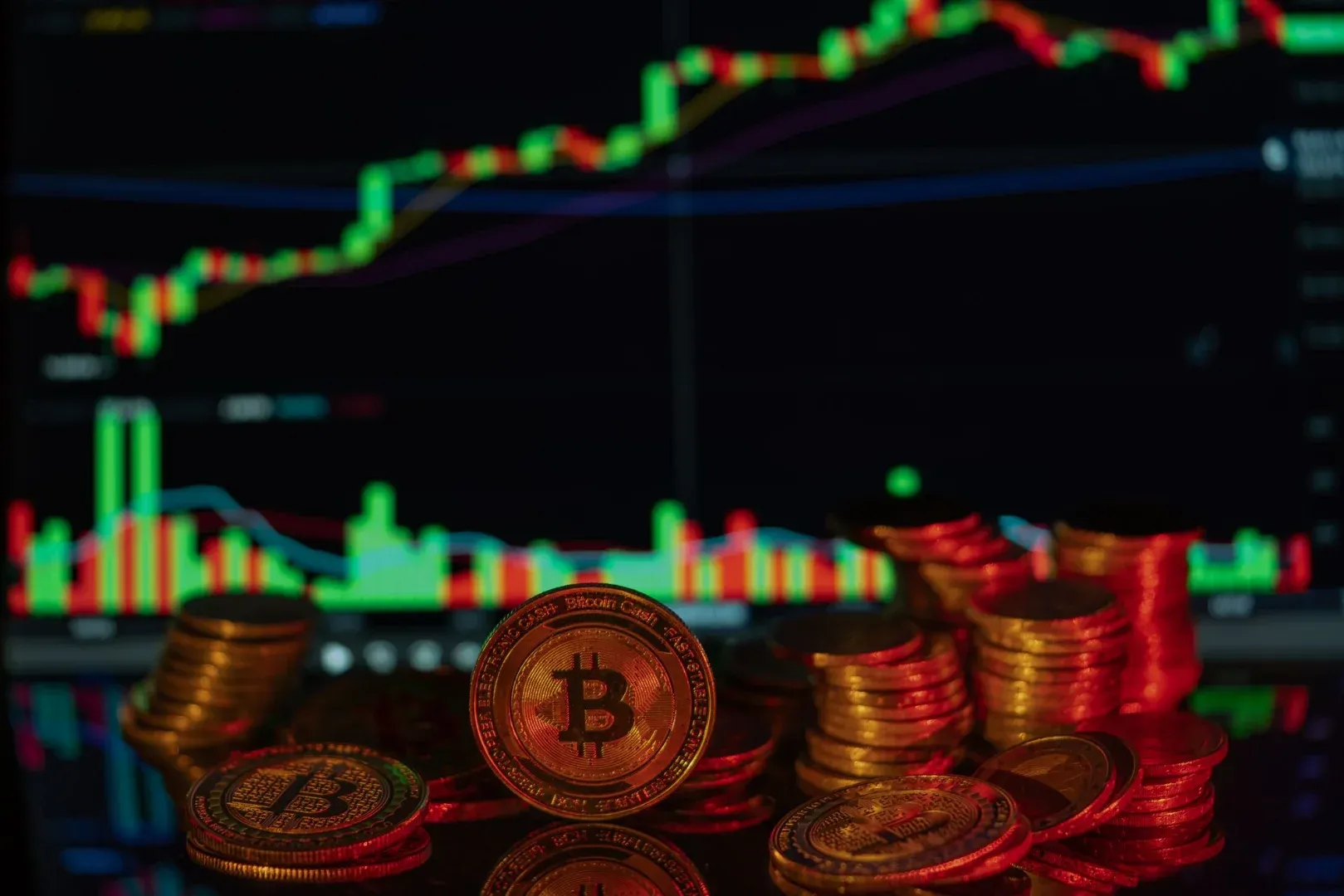 Stacks of Bitcoin coins with a financial market chart in the background, depicting cryptocurrency trading.