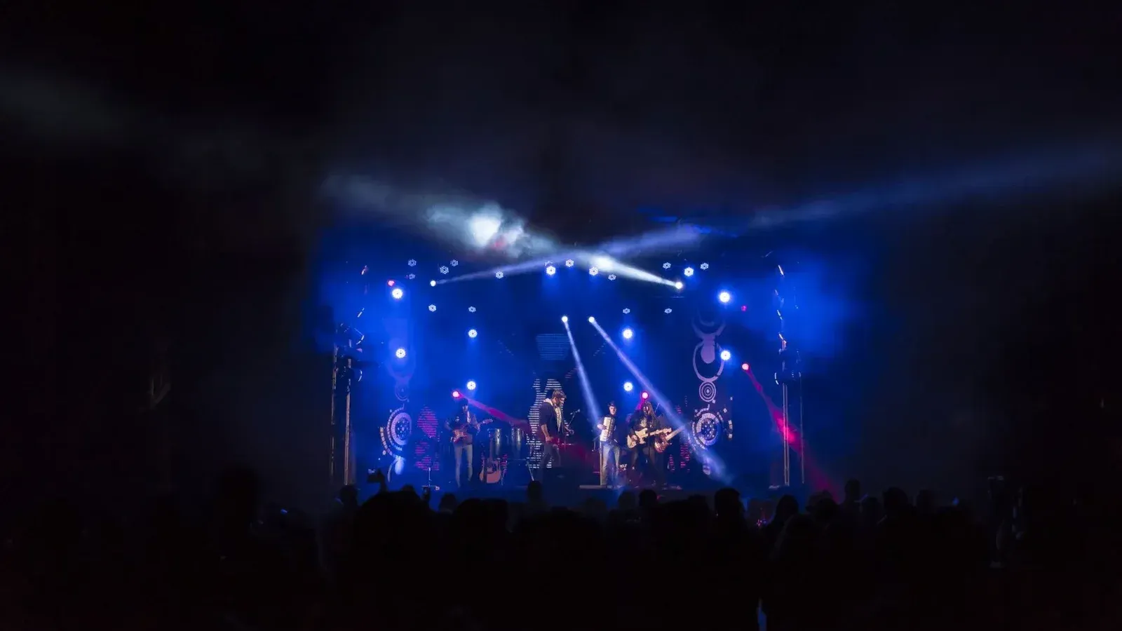 High-energy band performance on a stage with colorful lights and an engaged crowd.