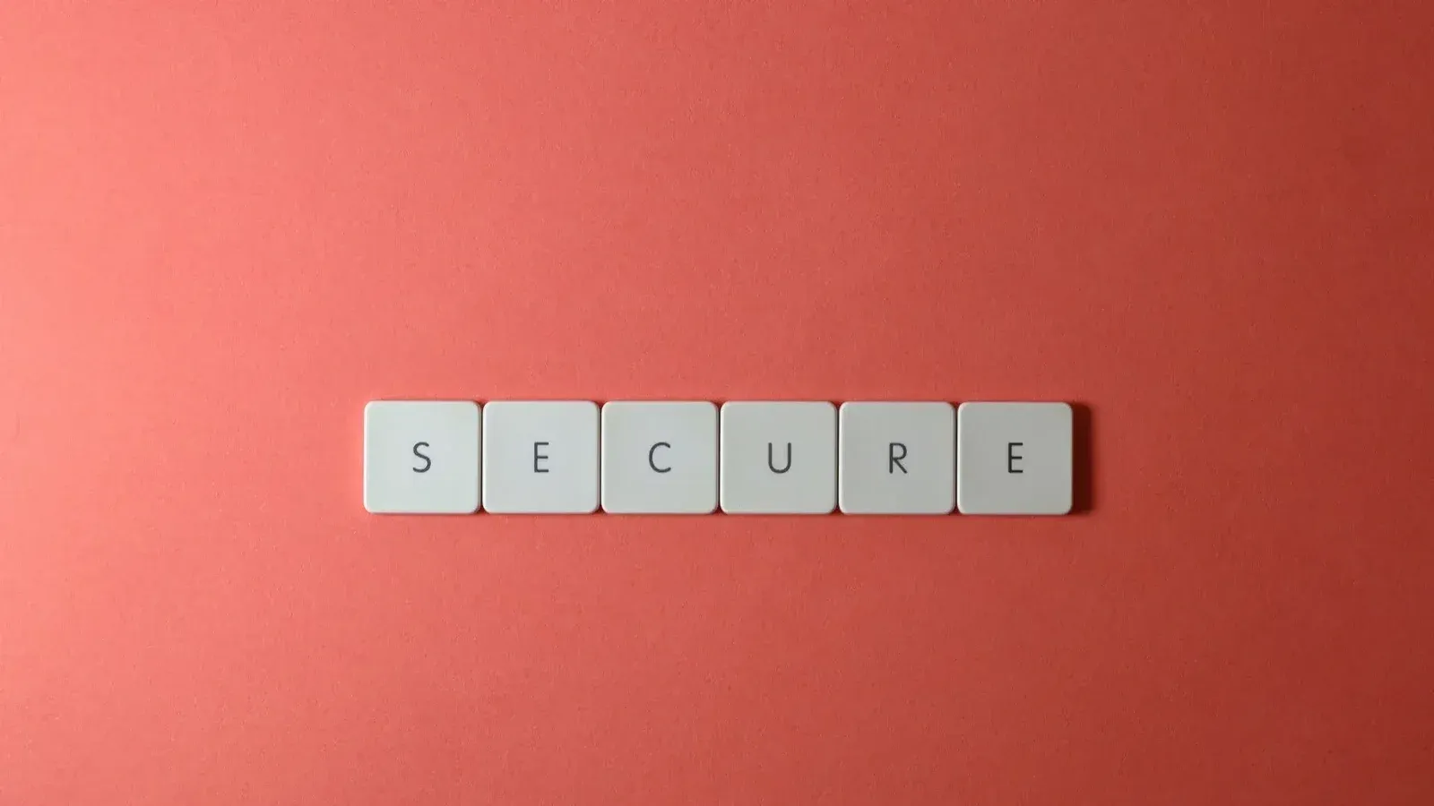 A close-up of the word 'Secure' spelled out with tiles on a red surface, ideal for security concepts.