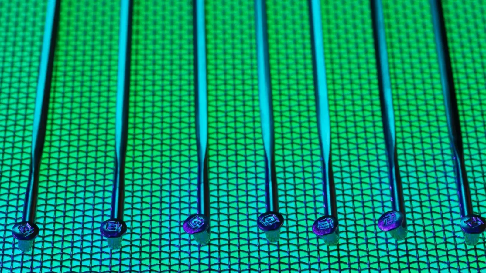 Vivid and detailed close-up of a patterned silicon wafer with vibrant green and blue colors.
