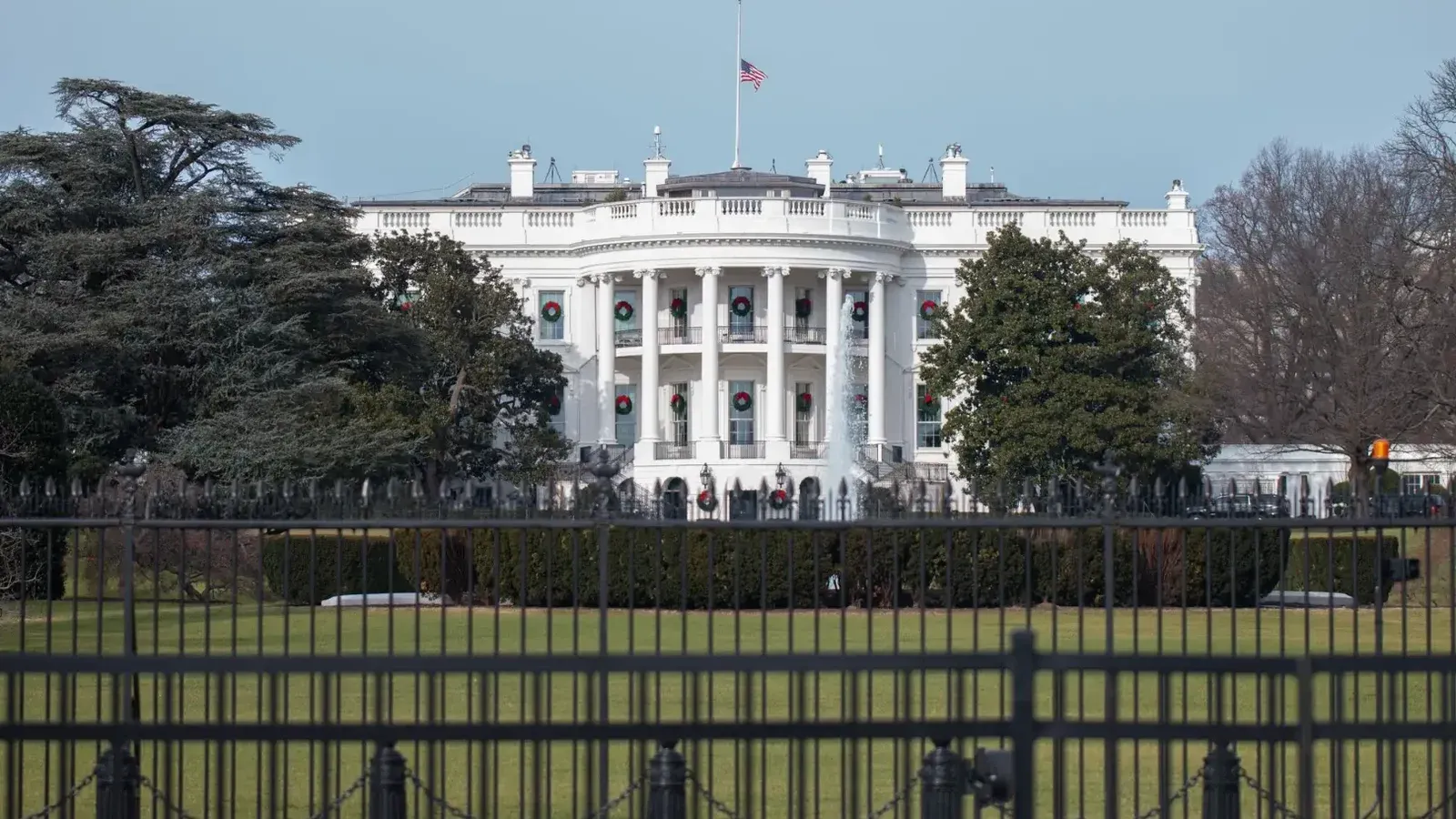 La icónica Casa Blanca con bandera americana y césped verde durante la temporada de invierno en Washington, DC.