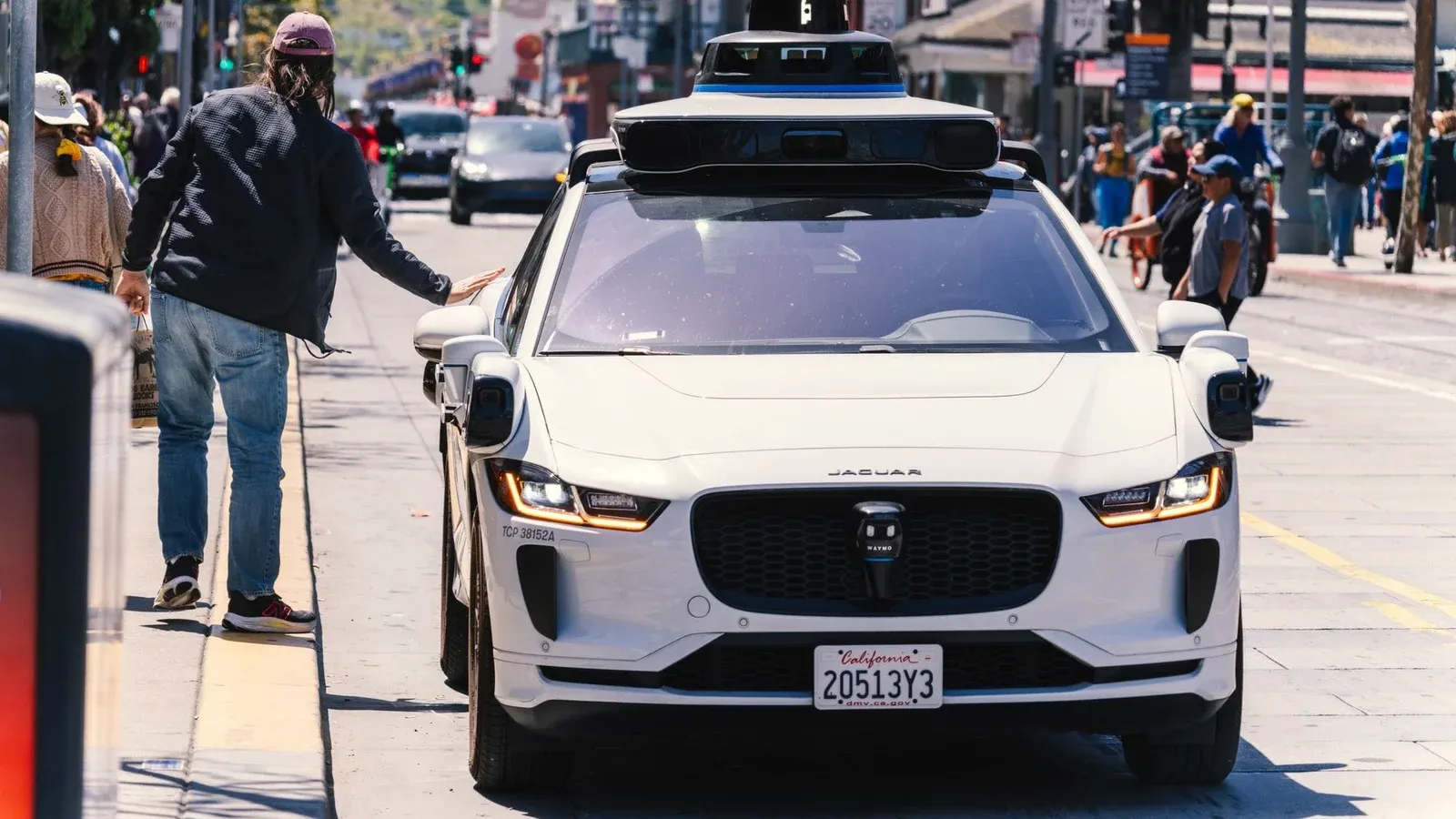 A self-driving car navigates through a bustling city street in San Francisco, capturing urban mobility in action.
