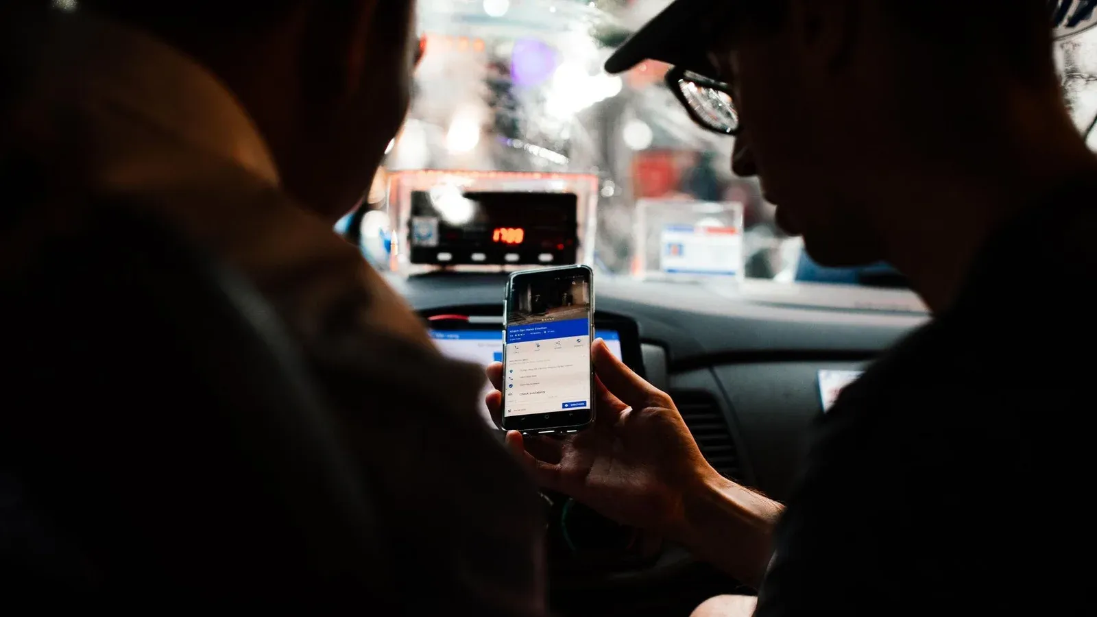 Two people using a smartphone for directions in a car at night.