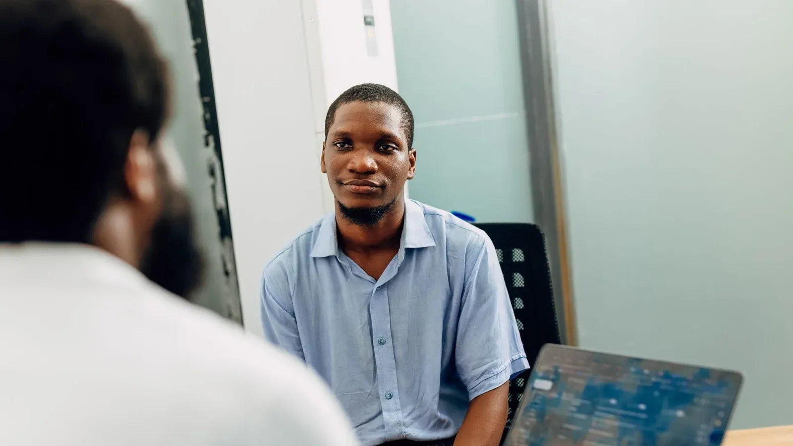 A business meeting in a modern office in Lagos, Nigeria featuring two professionals engaged in a discussion.