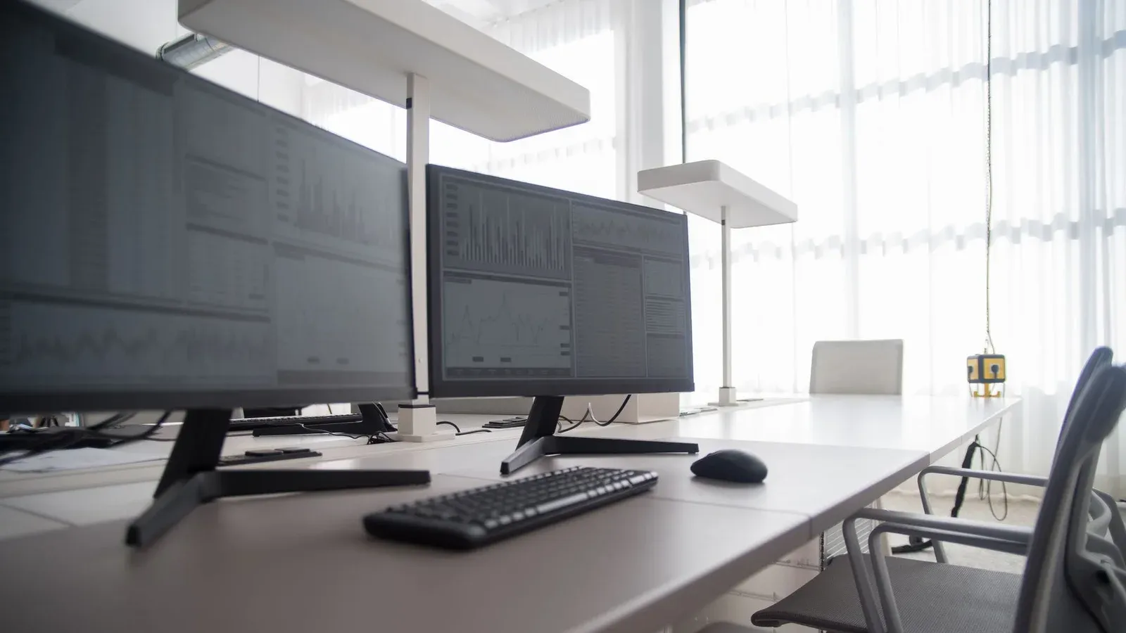 Stylish contemporary office featuring multiple computer monitors and ergonomic chairs.