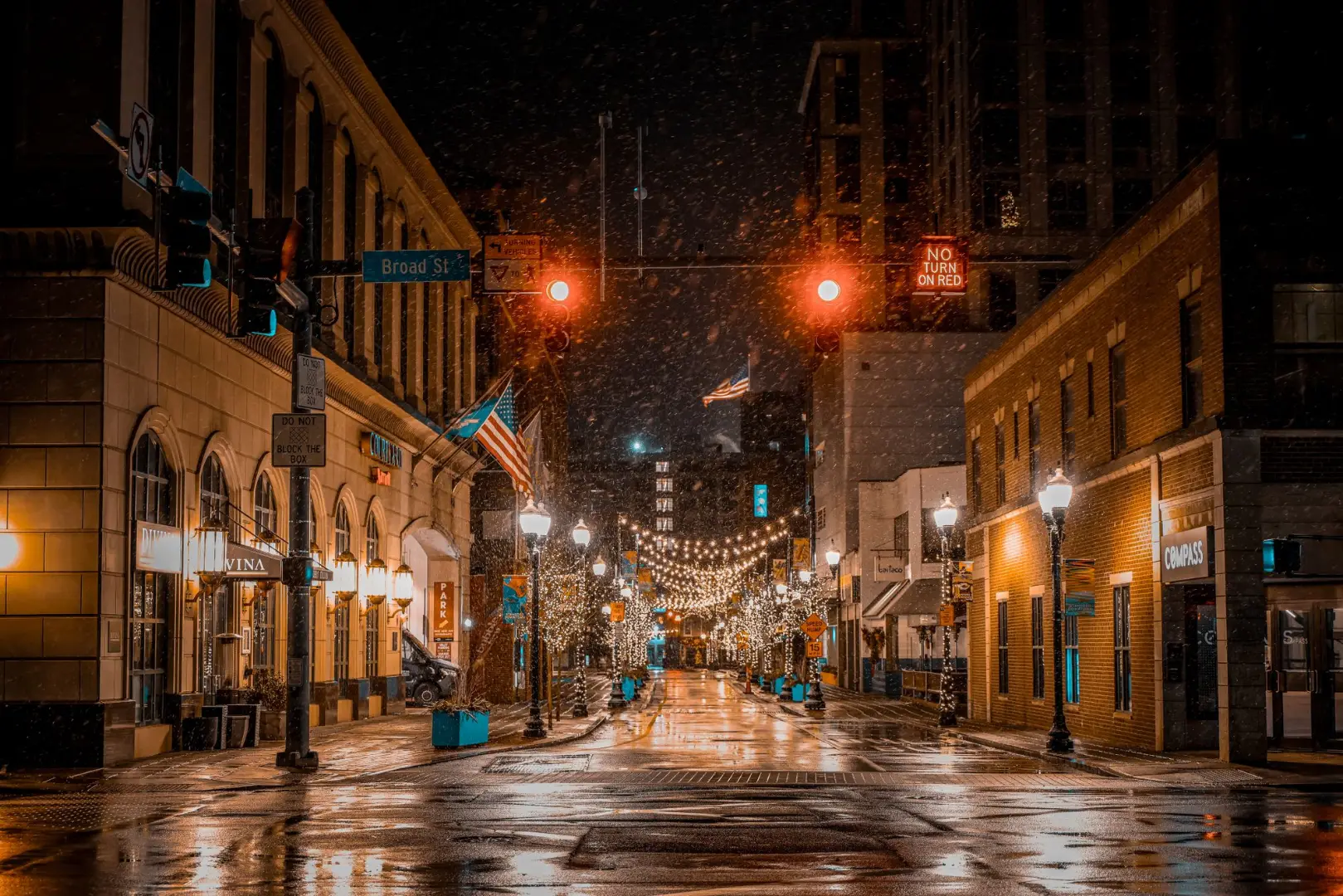 Una calle bellamente iluminada en Stamford por la noche durante las nevadas, mostrando decoraciones navideñas.