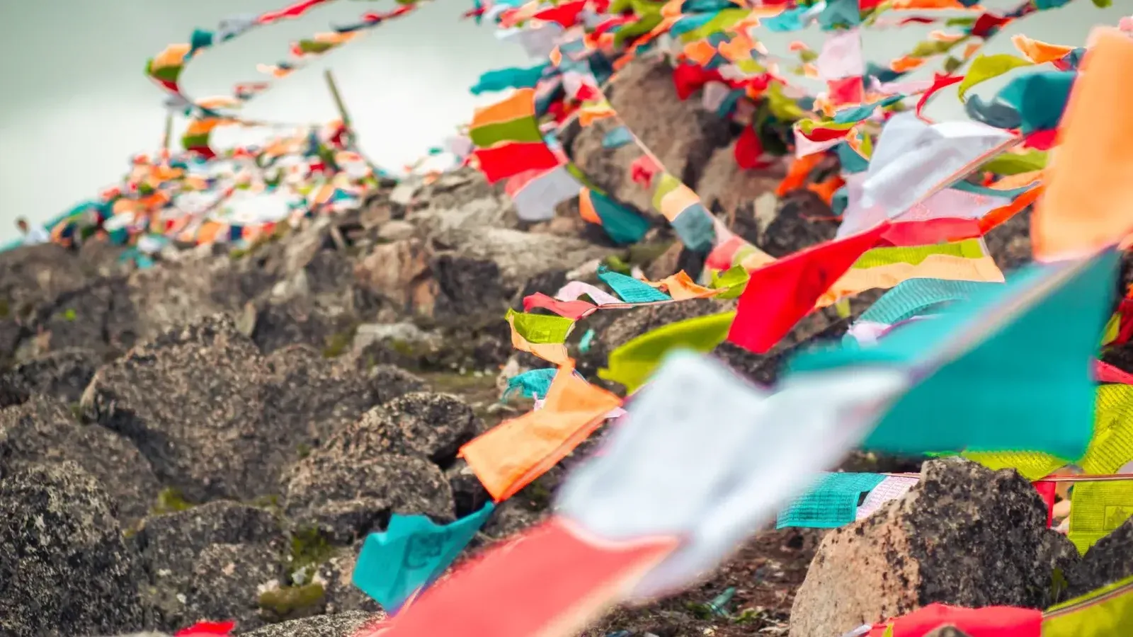 Vibrant Tibetan prayer flags fluttering on a rocky hillside in Garzê, China.