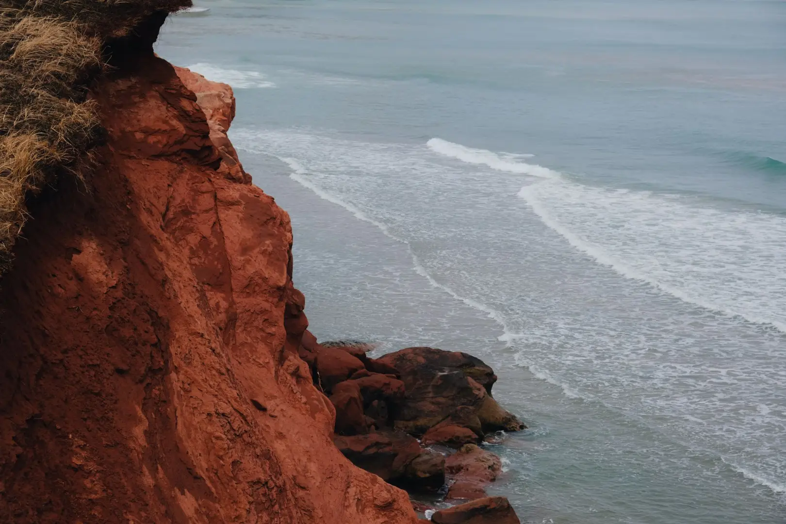 Una vista impresionante de los acantilados rojos con vistas al océano con suaves olas que se encuentran con la orilla.