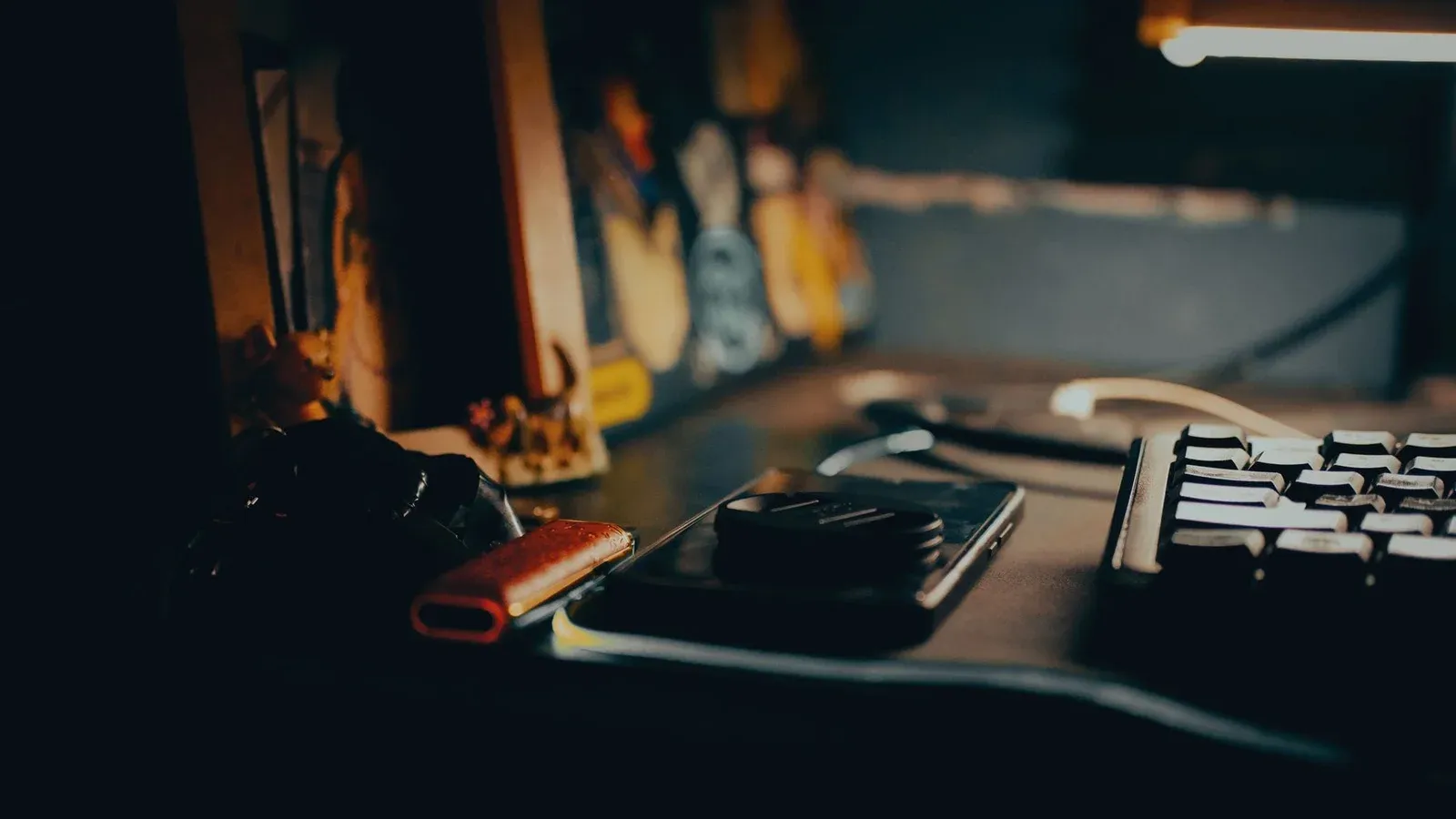 A dimly lit workspace featuring a keyboard, gadgets, and a warm ambient glow.