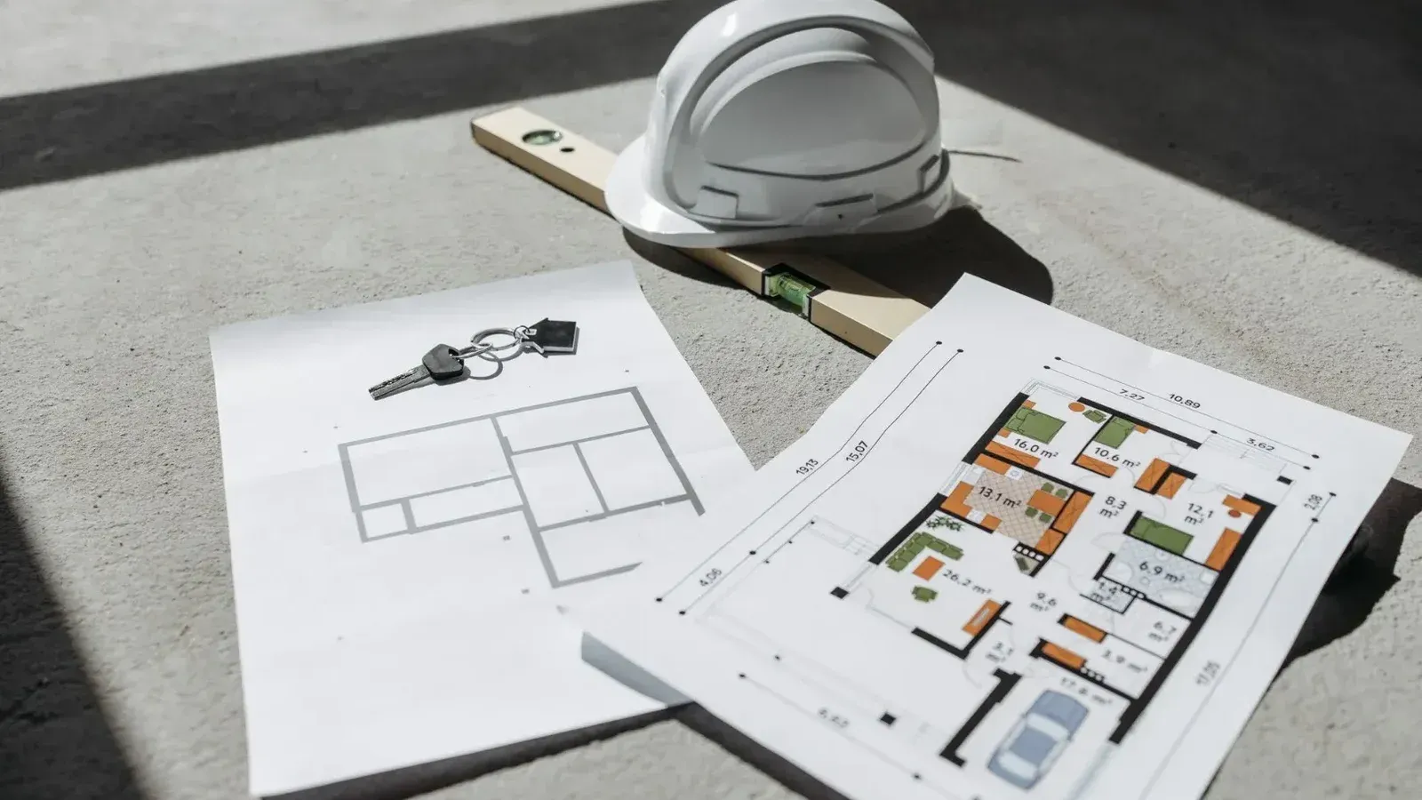 Architectural floor plans with helmet and keys on sunlit floor, perfect for real estate or construction themes.