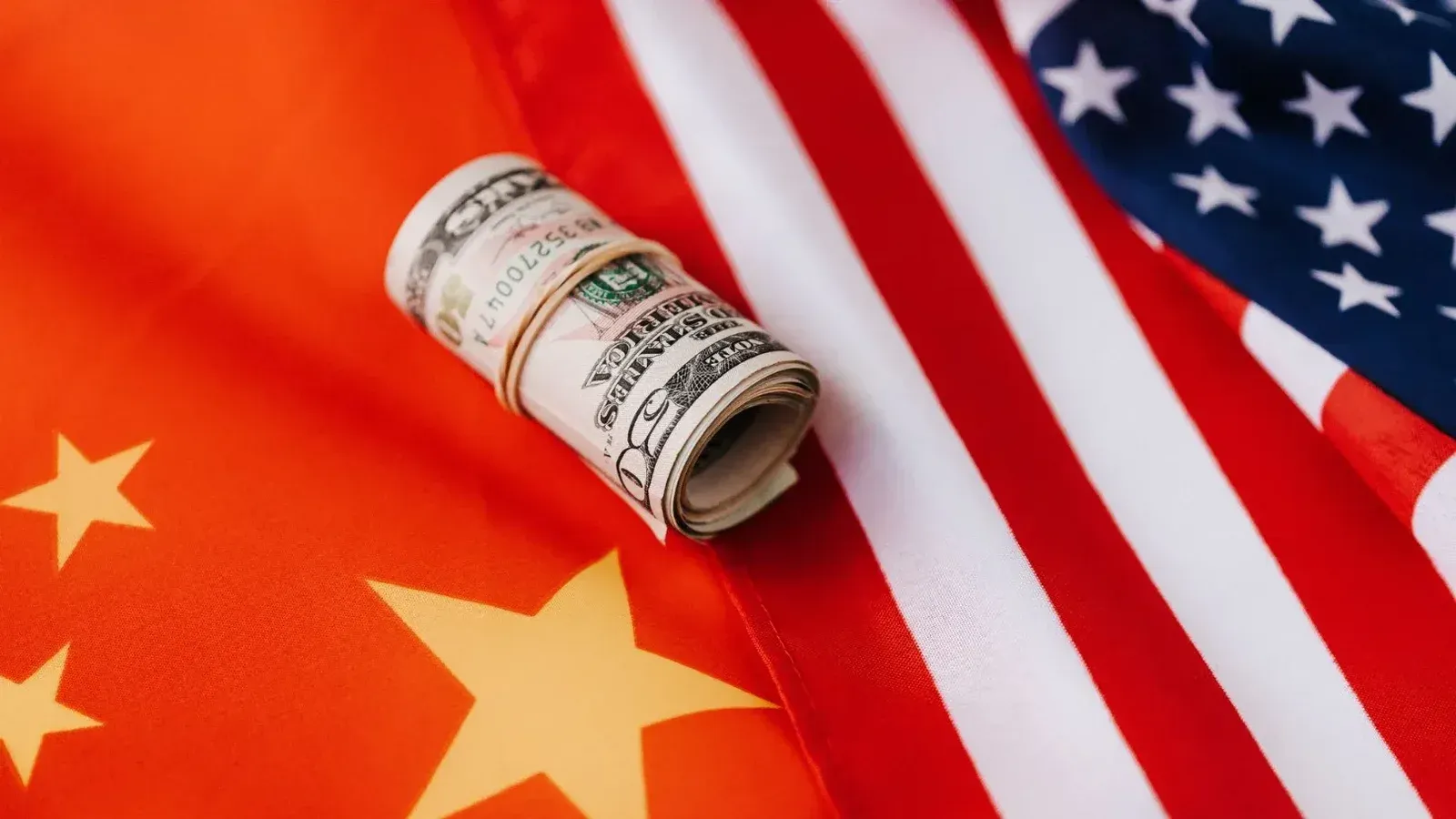 From above of roll of dollar bills tied with rubber band on bright American flag with stars and stripes symbolizing unity and peace