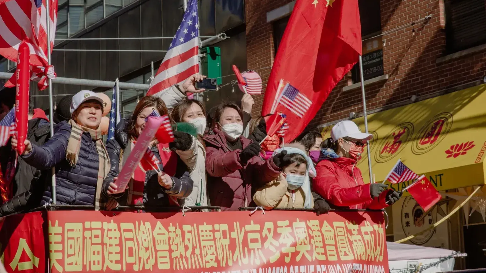 People celebrate with flags during a Chinatown parade, showcasing a blend of American and Chinese culture.